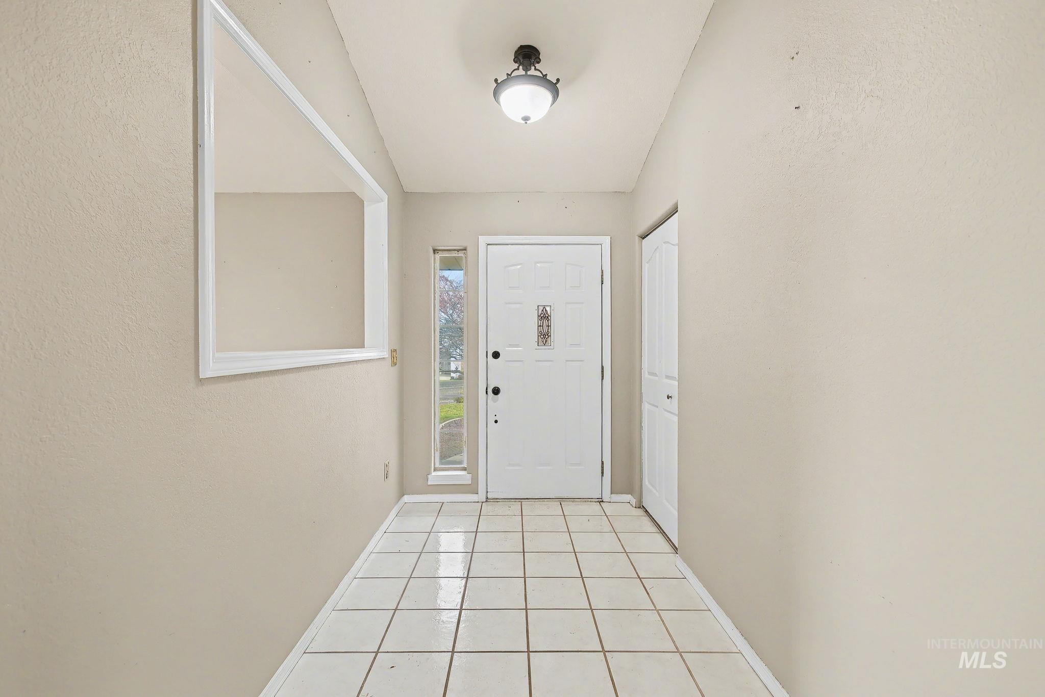 Doorway with tile patterned flooring and baseboards