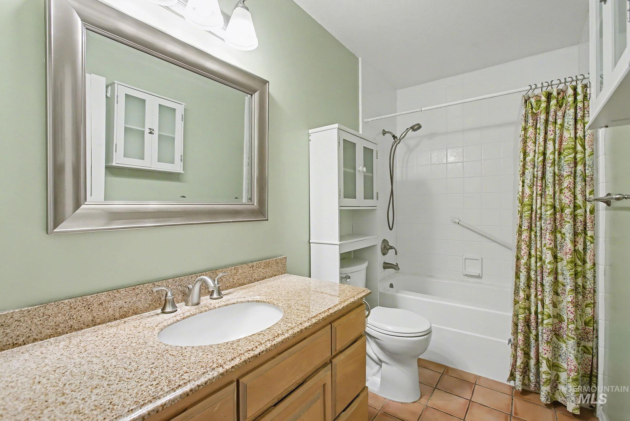Bathroom with vanity, shower / bathtub combination with curtain, and light tile patterned flooring
