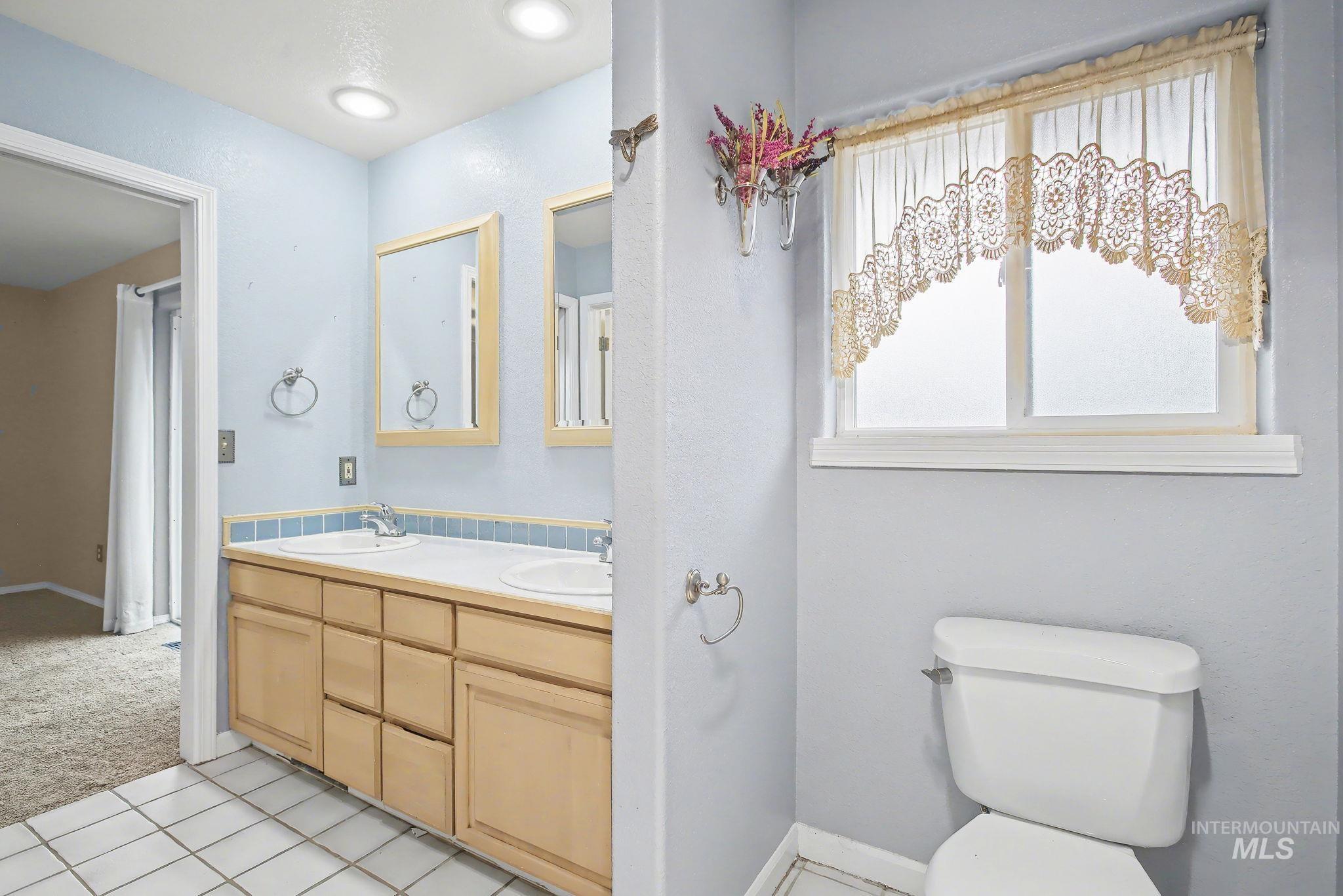 Bathroom featuring light carpet, double vanity, and light tile patterned floors