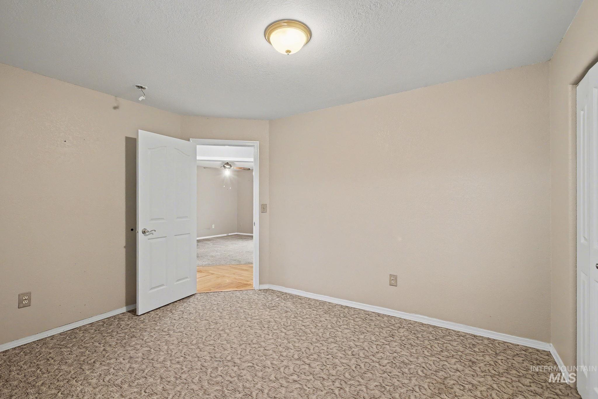 Unfurnished room with a textured ceiling and light carpet