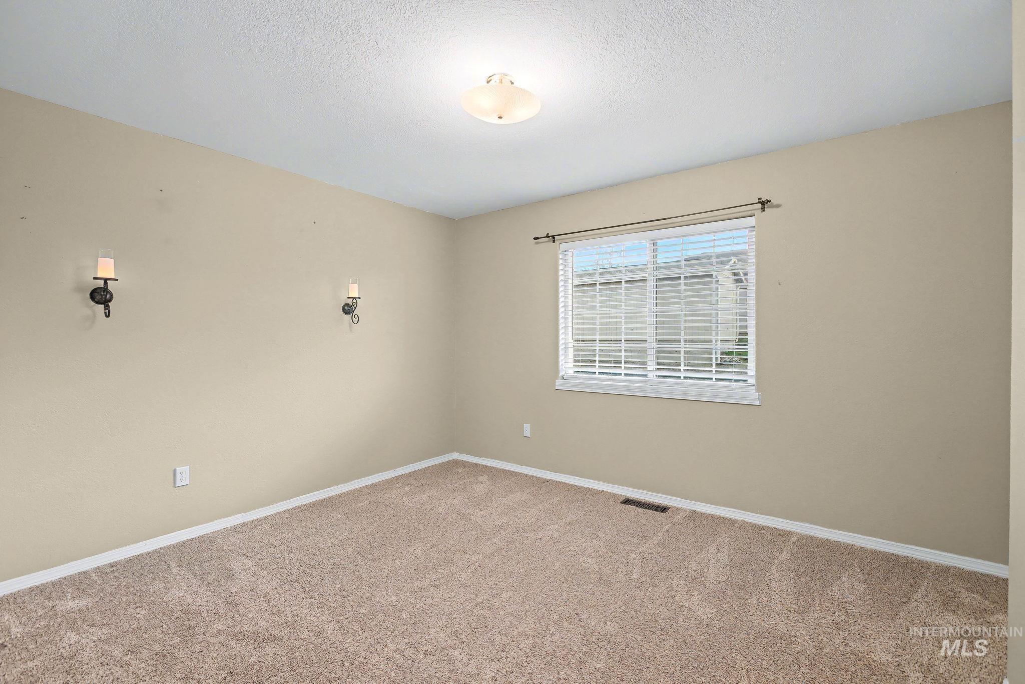 Carpeted empty room featuring baseboards and a textured ceiling