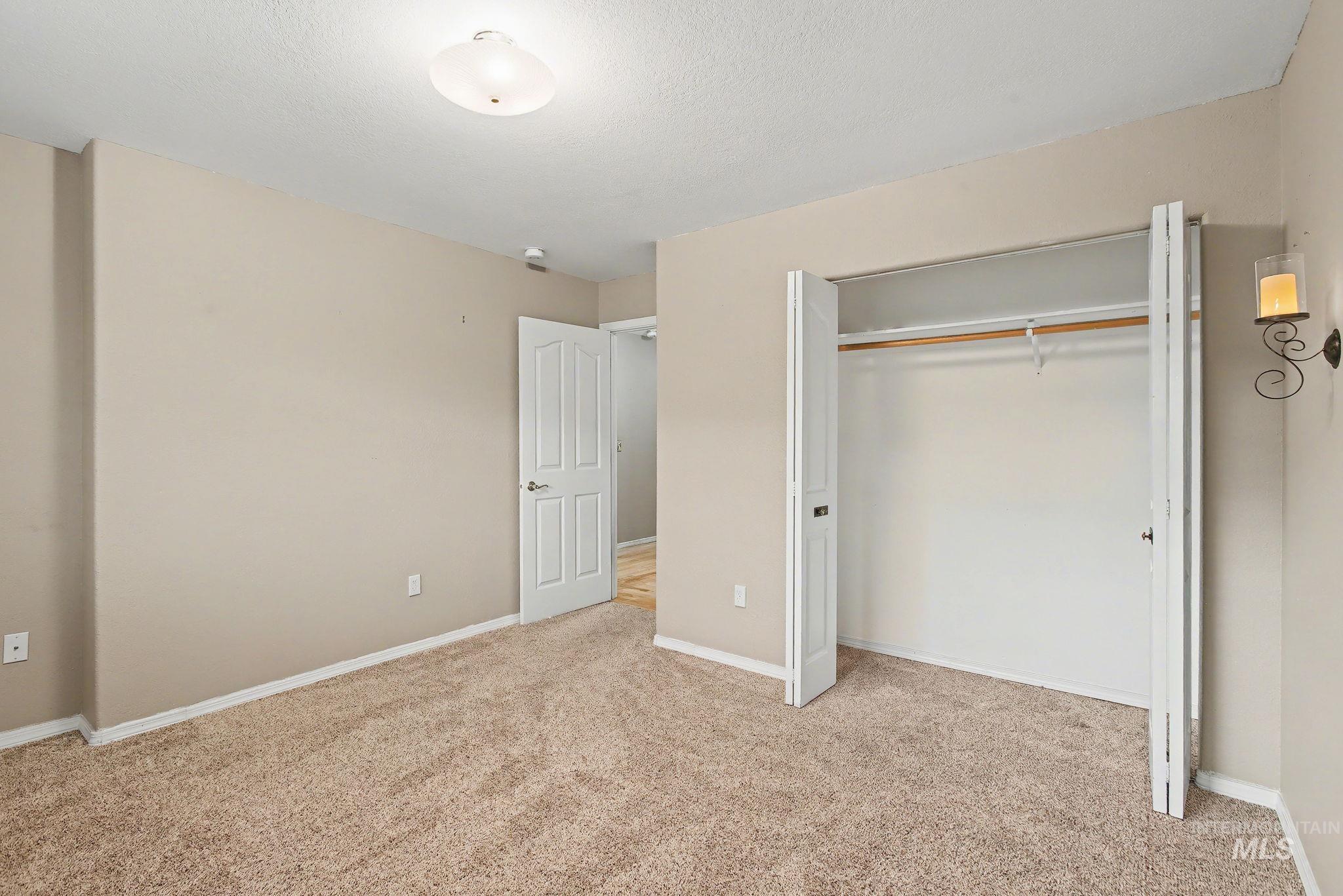 Unfurnished bedroom with light carpet, a closet, and a textured ceiling