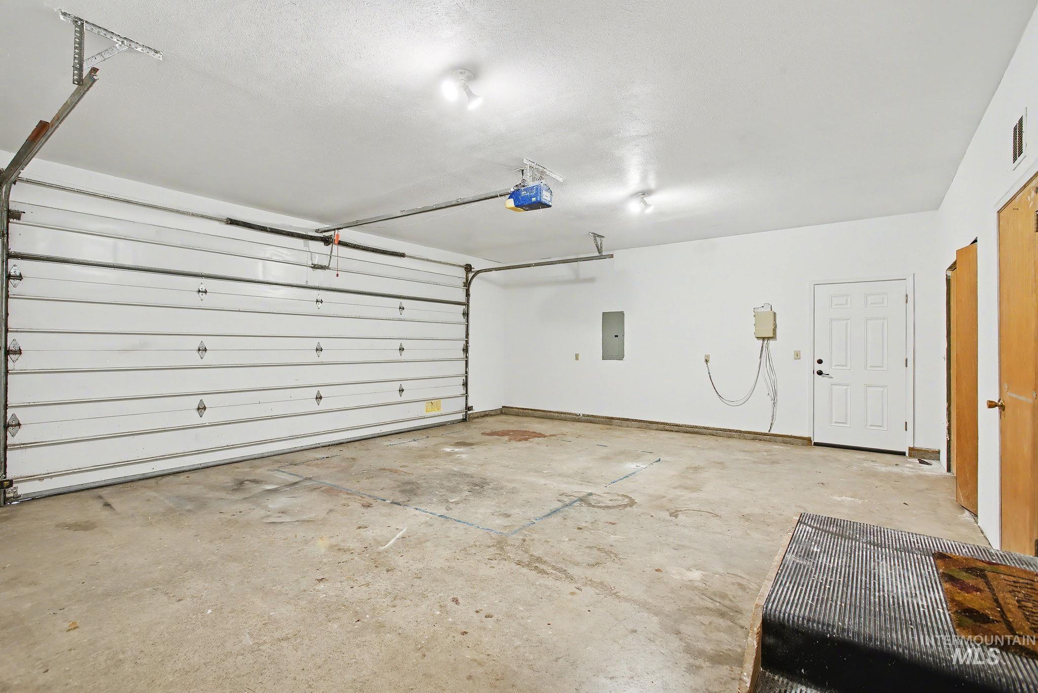 Garage featuring electric panel and a garage door opener