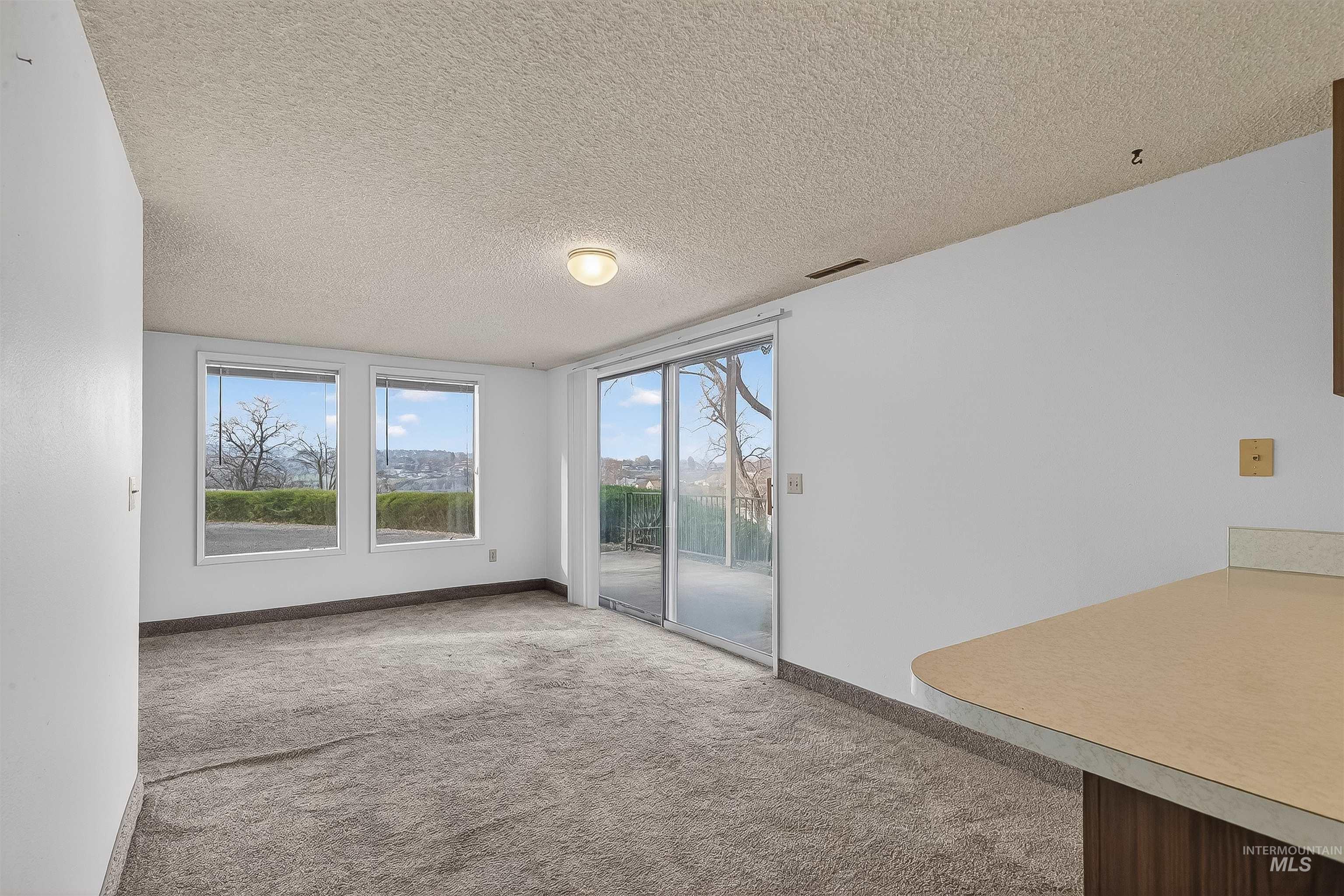 Carpeted empty room featuring a textured ceiling and baseboards