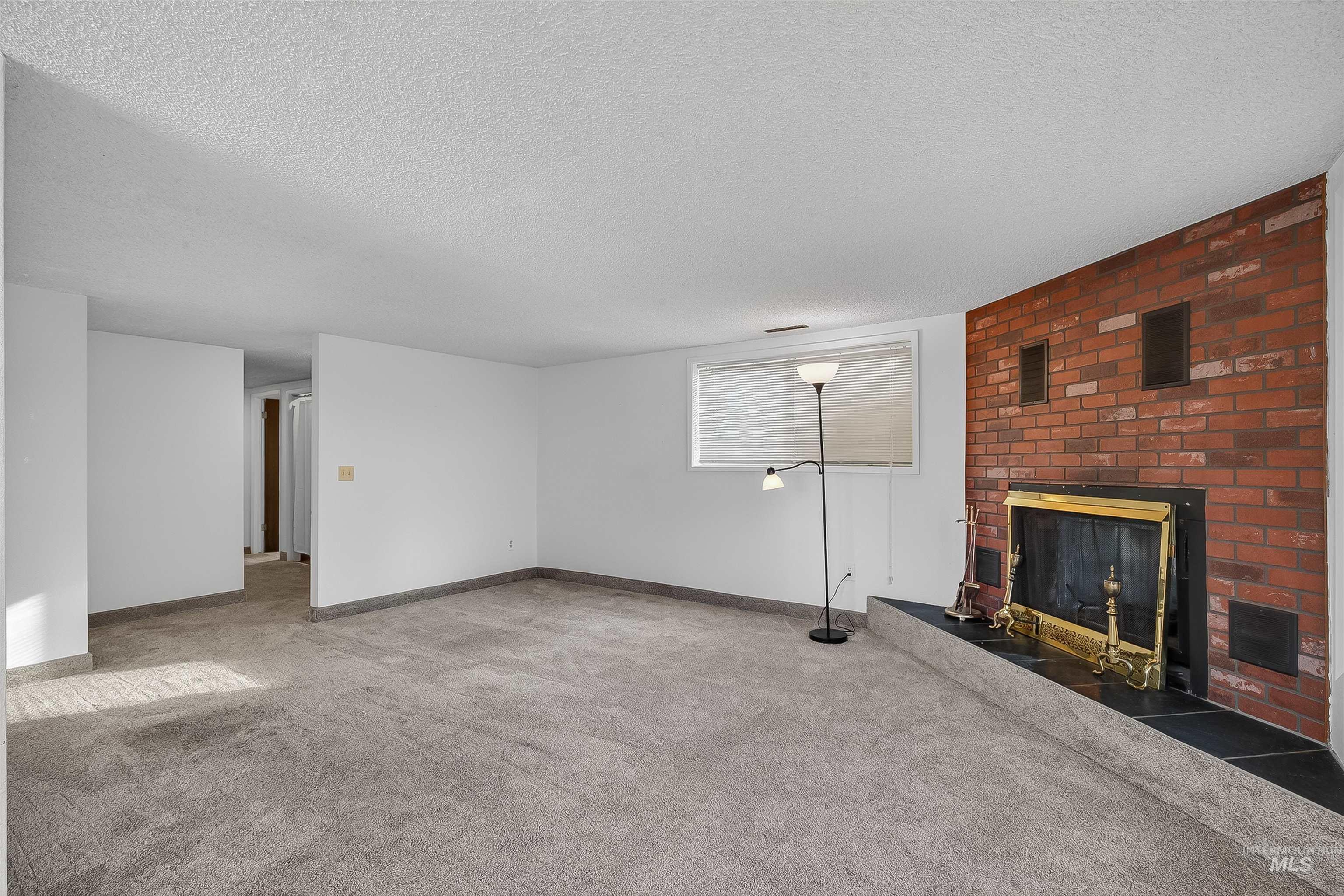 Unfurnished living room with a textured ceiling, a fireplace, and carpet