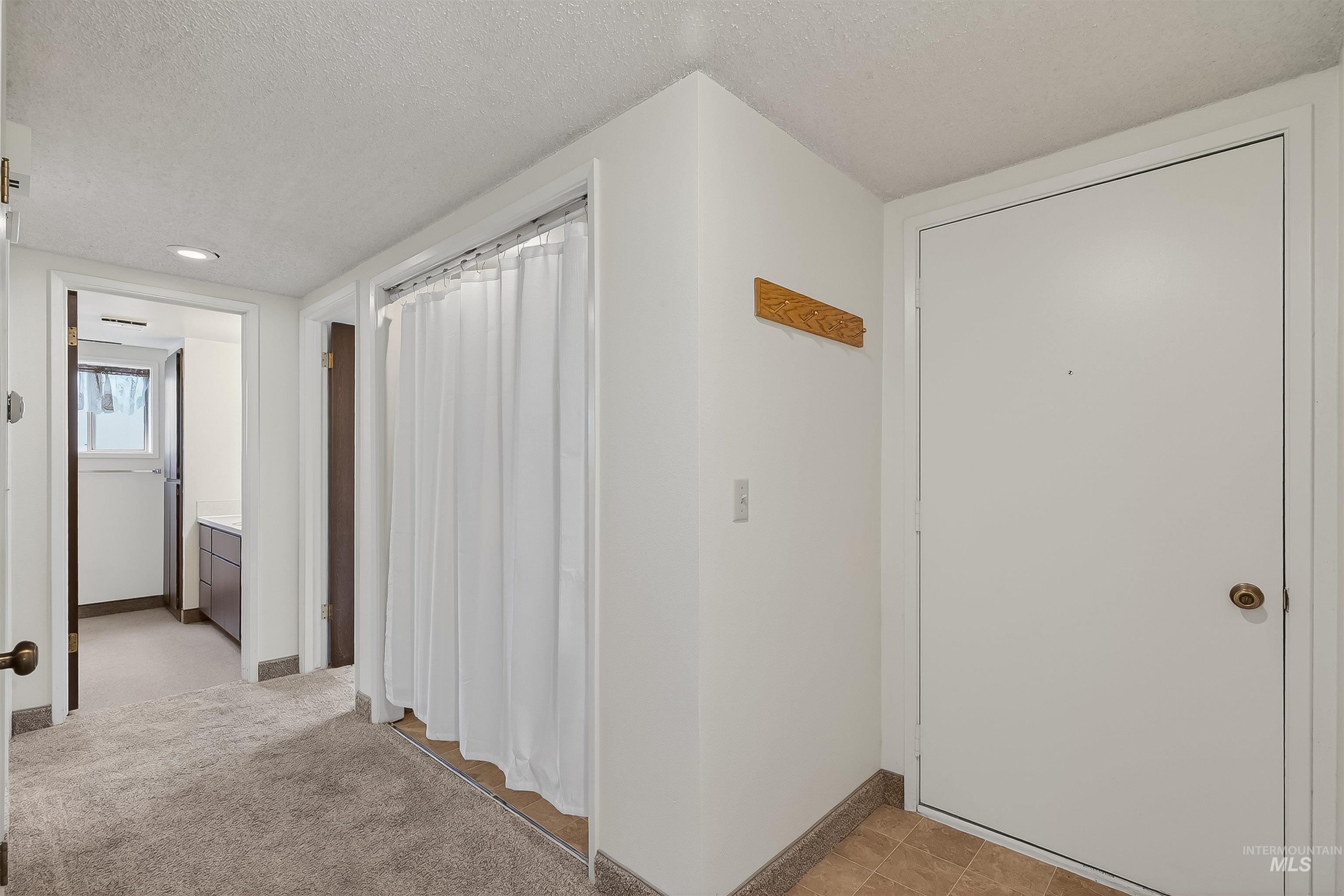 Corridor with a textured ceiling and light colored carpet