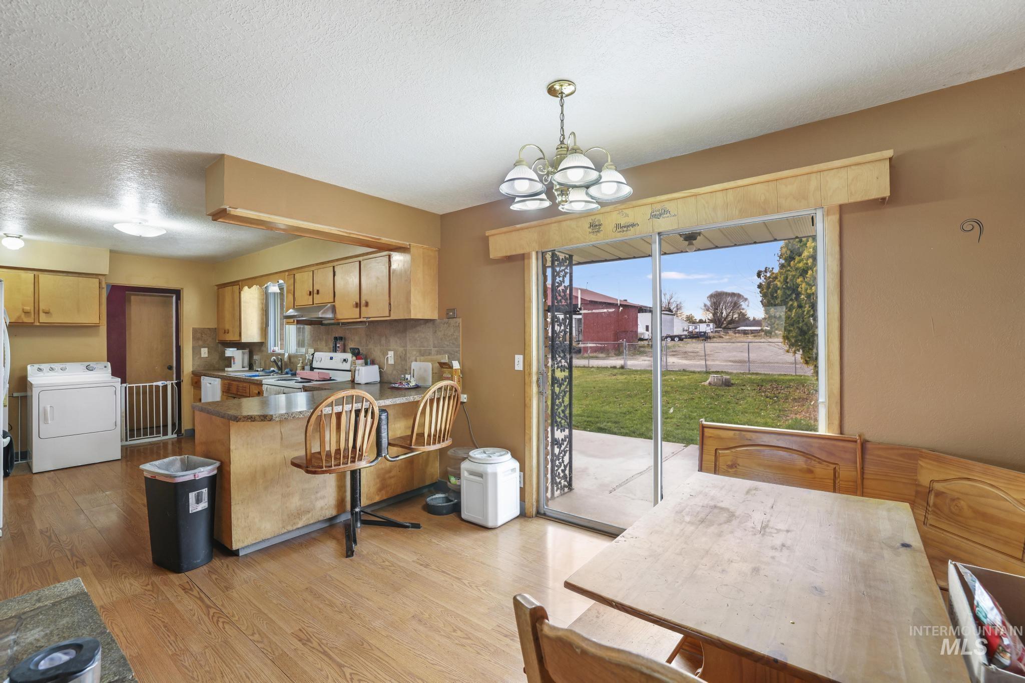 Kitchen featuring a peninsula, washer / clothes dryer, backsplash, a chandelier, and a textured ceiling