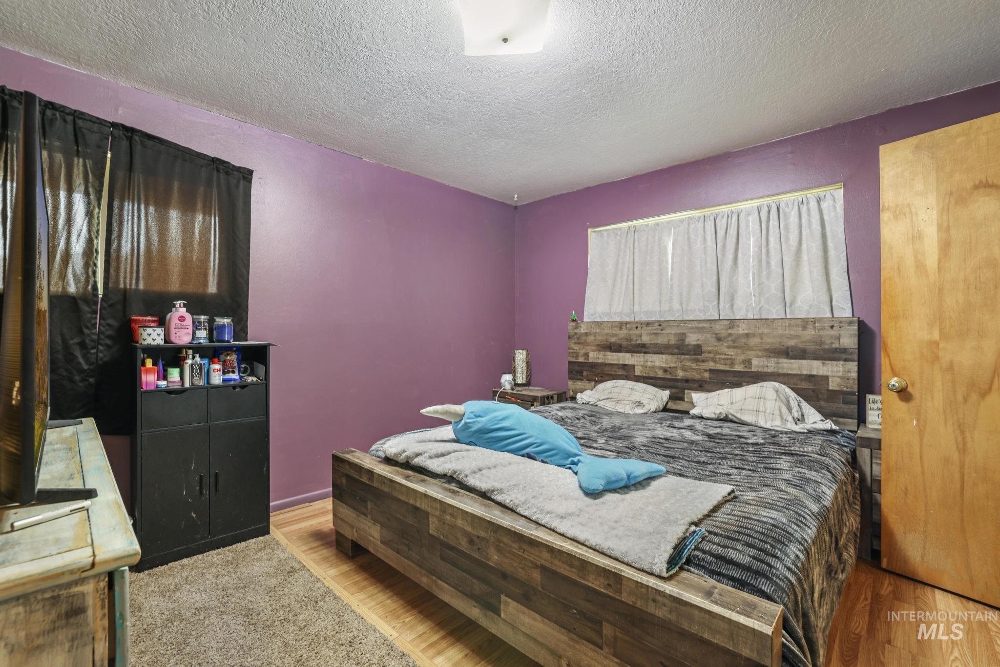 Bedroom with a textured ceiling and wood finished floors