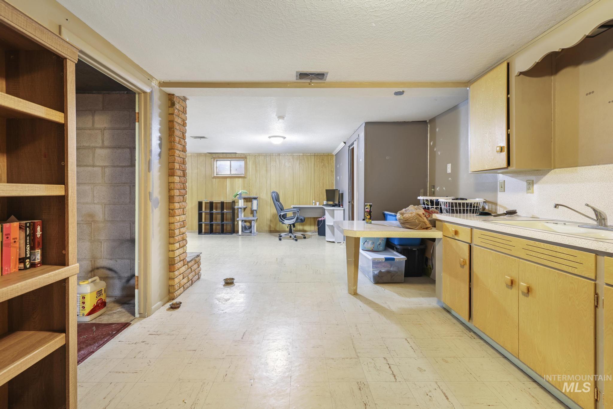 Kitchen featuring light flooring, a desk, light countertops, wooden walls, and a textured ceiling