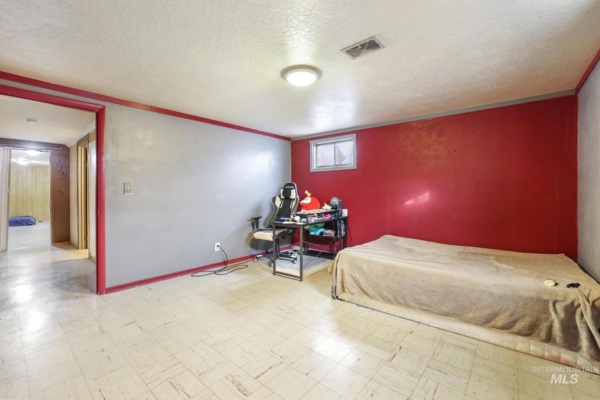 Bedroom with tile patterned floors, a textured ceiling, a desk, and ornamental molding