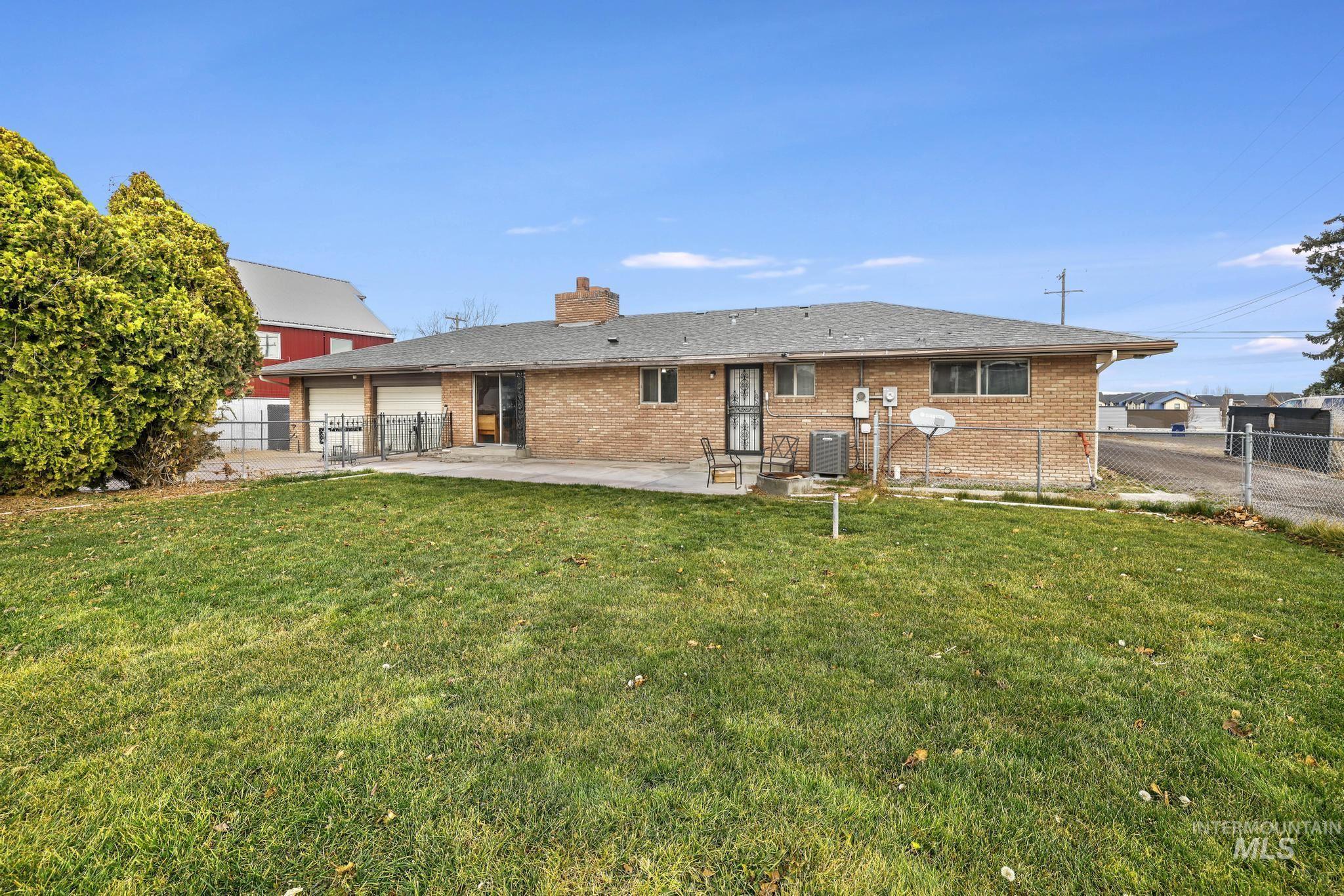 Back of property with brick siding, a patio area, a chimney, and a shingled roof