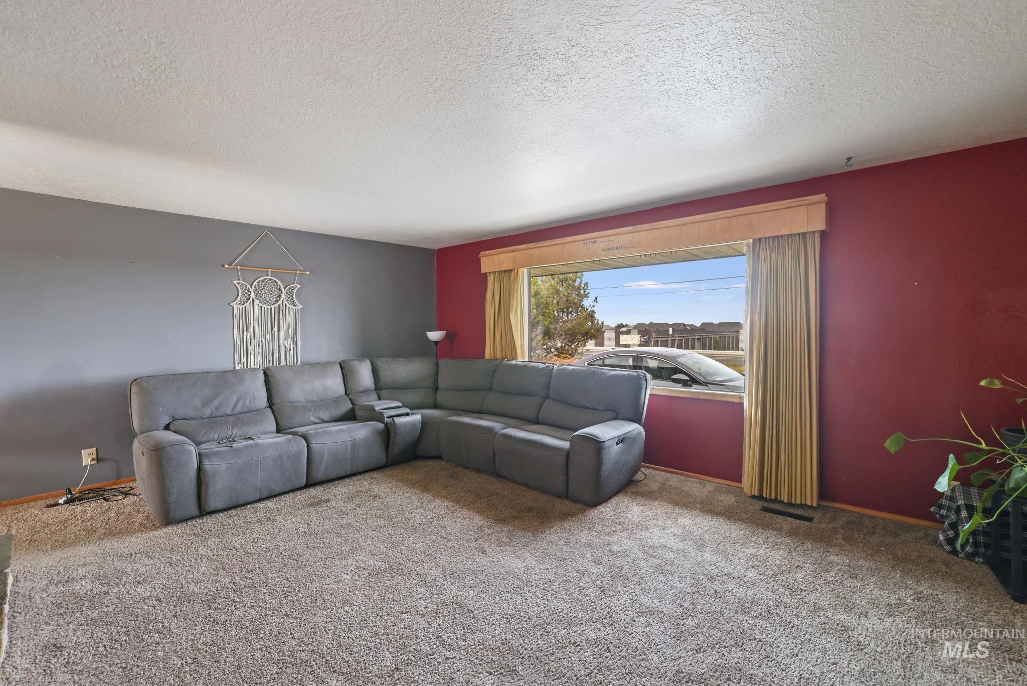 Living area with a textured ceiling and carpet flooring