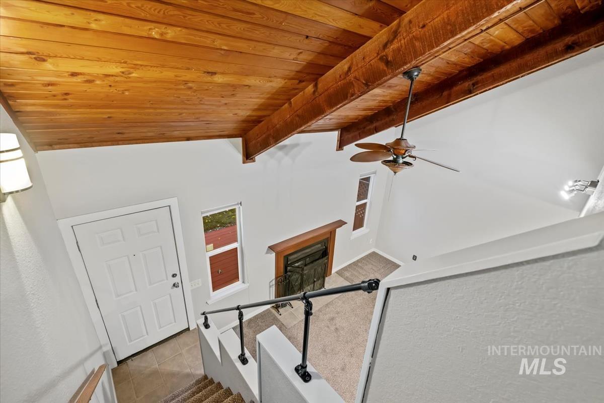 Tiled foyer with wood ceiling, stairway, a fireplace, and ceiling fan