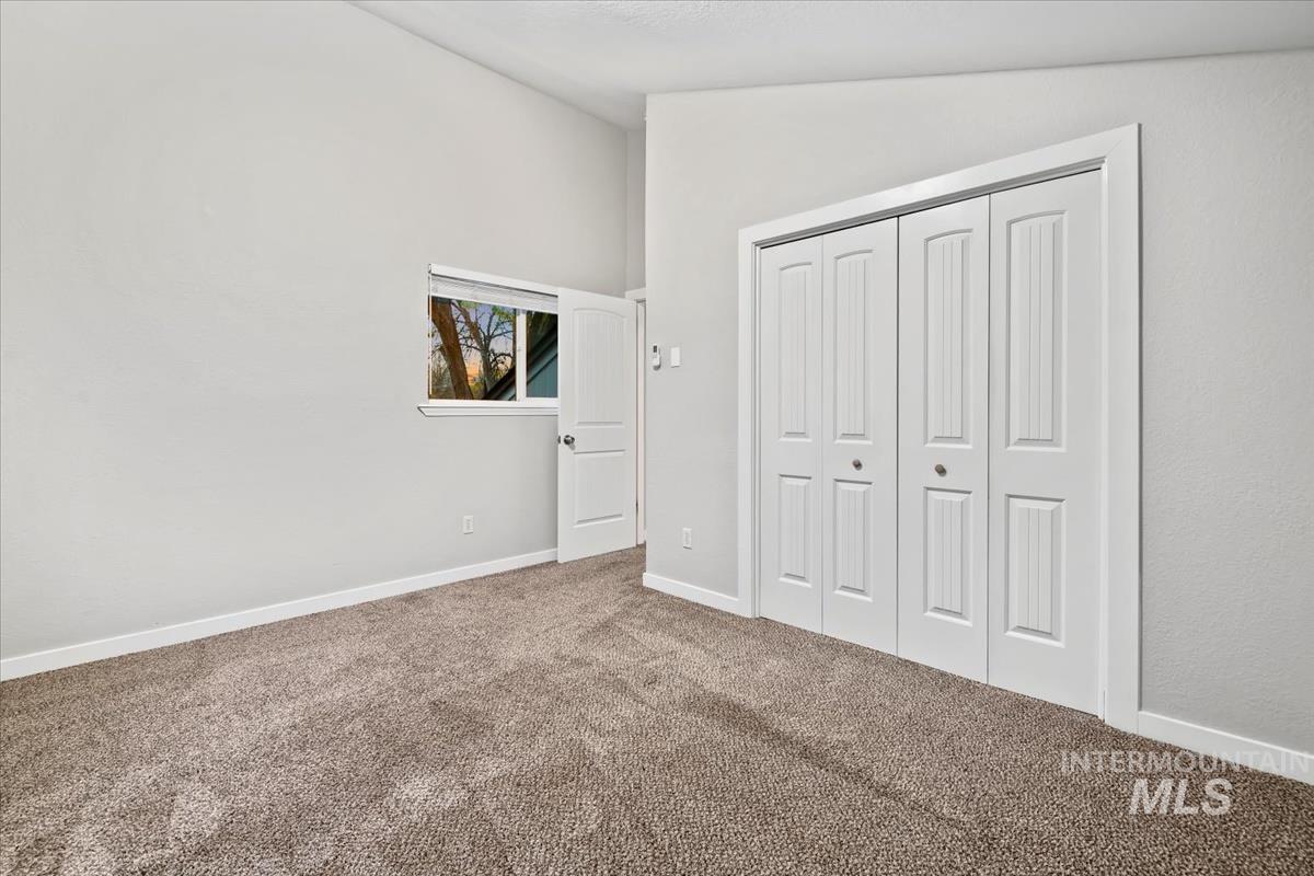 Unfurnished bedroom featuring vaulted ceiling, carpet floors, and a closet