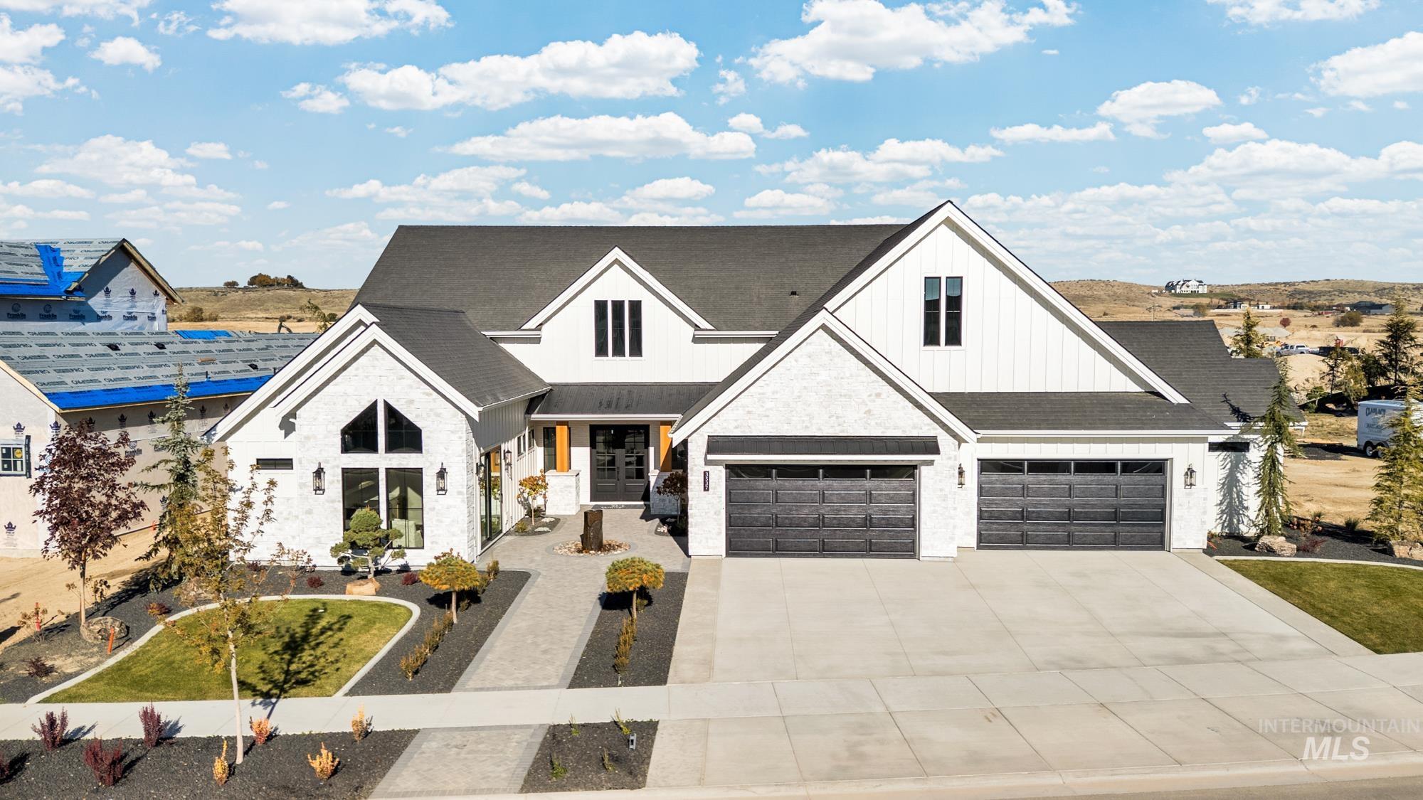 Modern farmhouse style home featuring board and batten siding, covered porch, concrete driveway, stone siding, and roof with shingles
