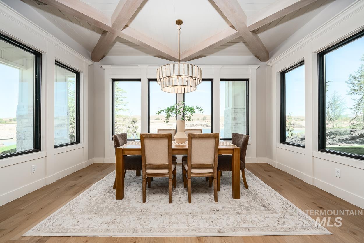 Dining area featuring beam ceiling, healthy amount of natural light, coffered ceiling, light wood-type flooring, and a chandelier