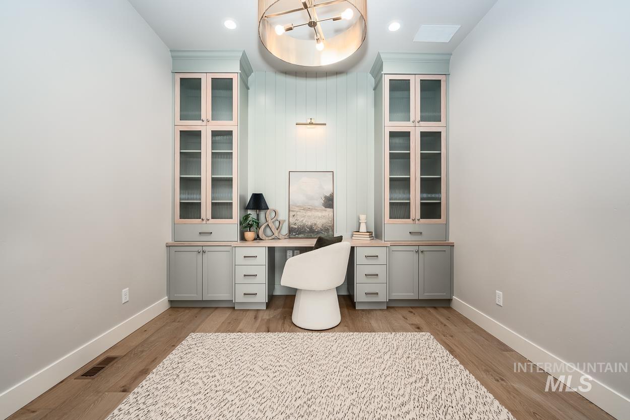 Home office with built in study area, light wood-type flooring, and recessed lighting