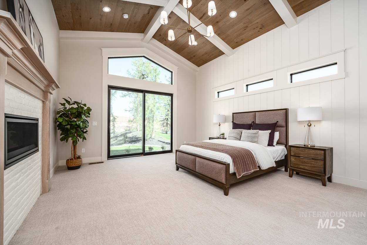 Bedroom with a glass covered fireplace, high vaulted ceiling, light carpet, and a wooden ceiling with exposed beams