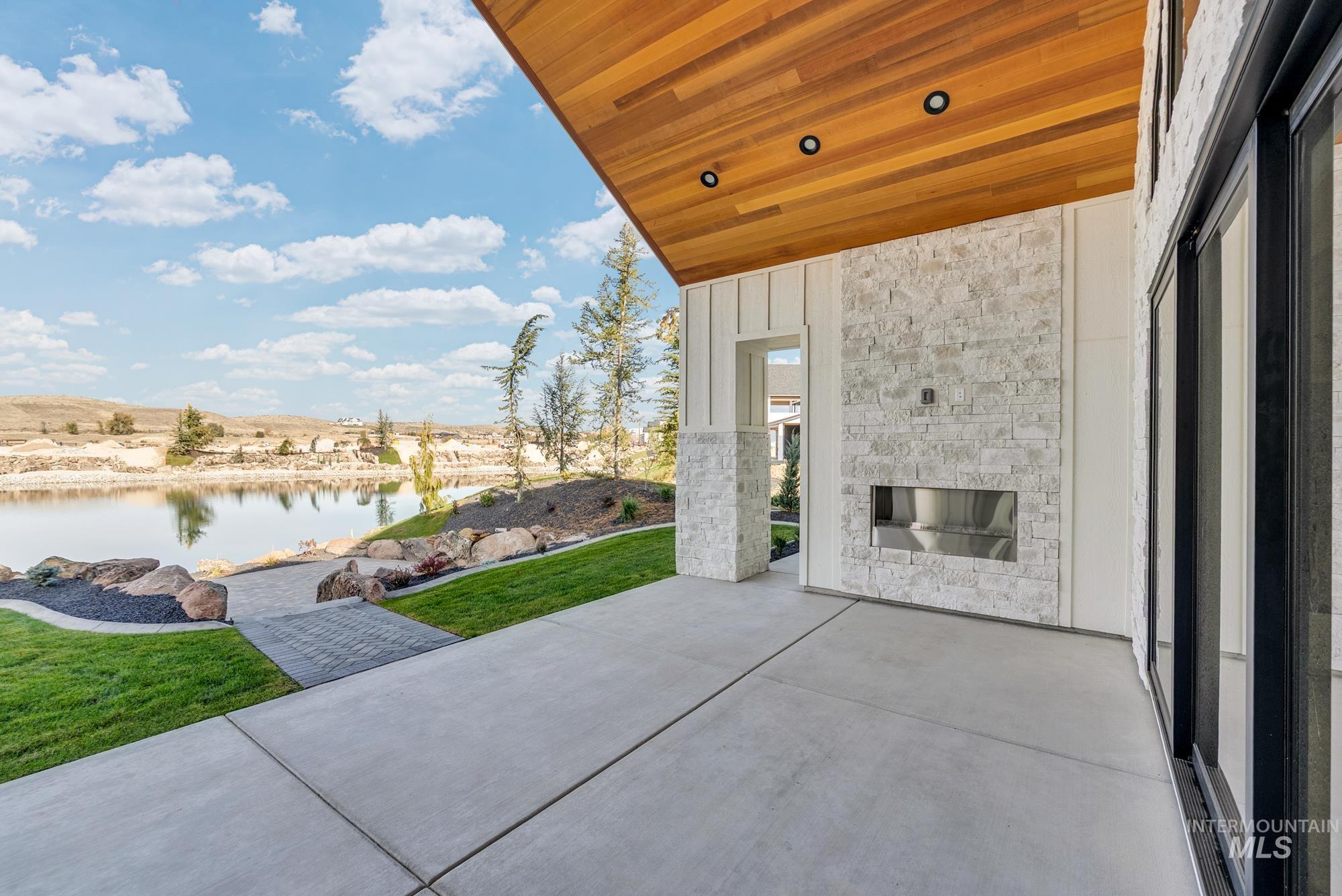 View of patio / terrace featuring an outdoor stone fireplace and a water view