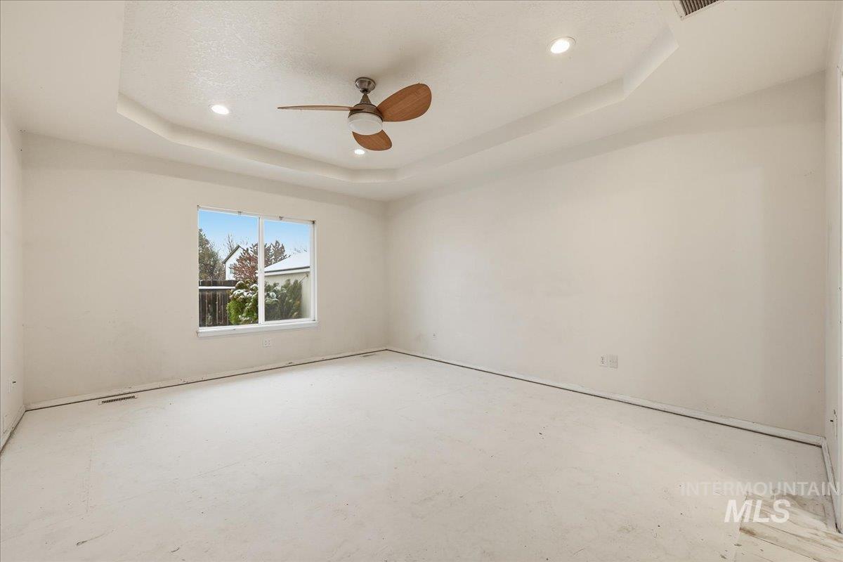 Master bedroom with a raised ceiling, ceiling fan, tray ceiling and recessed lighting