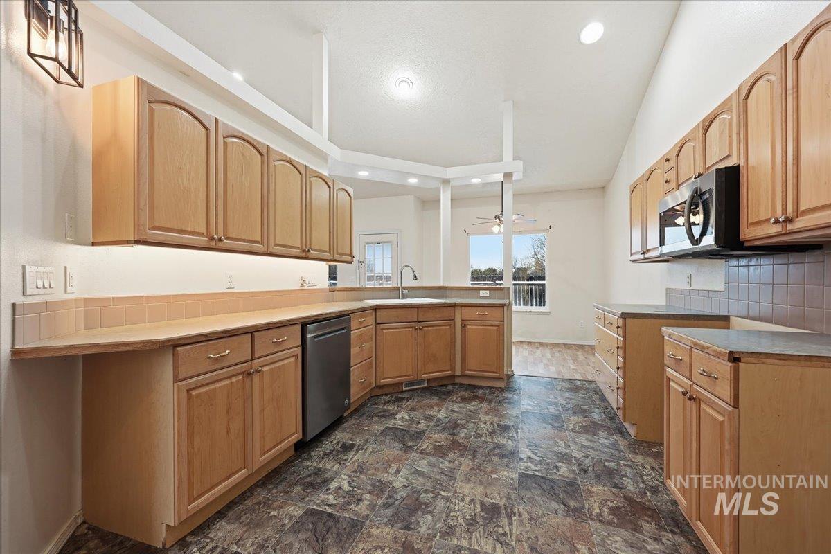 Kitchen with decorative backsplash, vinyl flooring, new microwave, dishwasher, disposal, under counter and recessed lighting.
