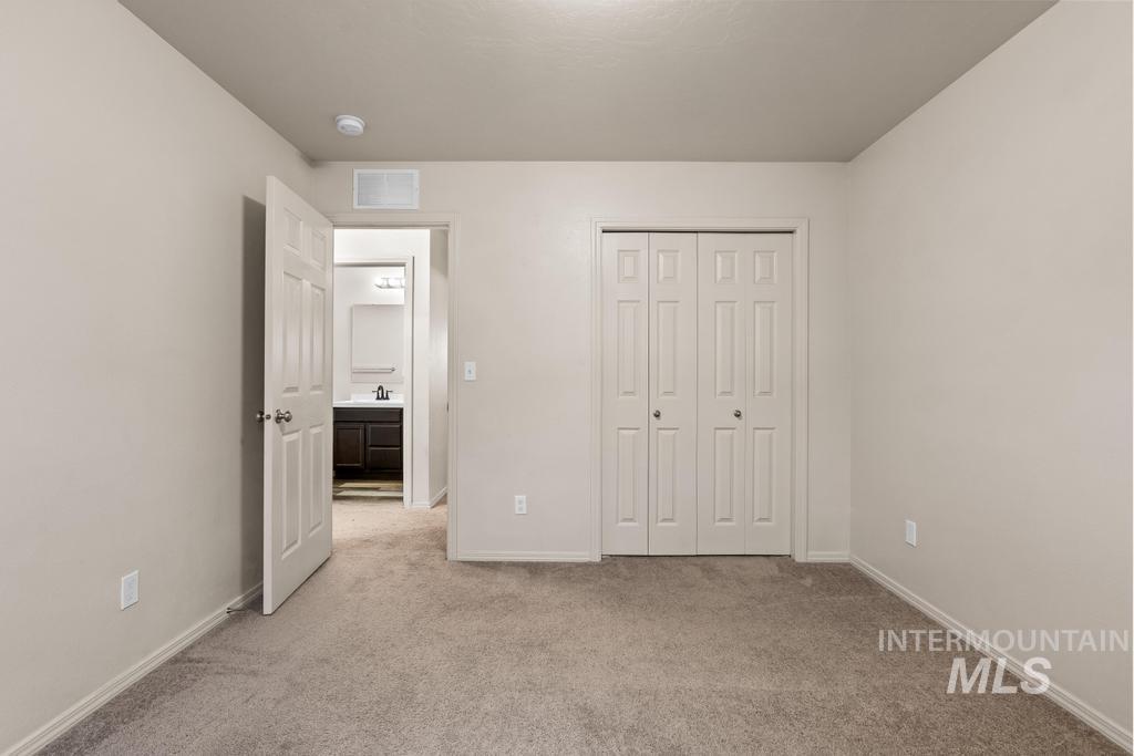 Unfurnished bedroom featuring light carpet and a closet
