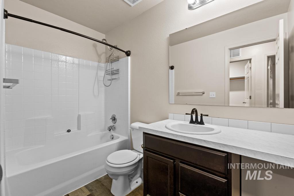 Bathroom featuring vanity, shower / bathtub combination, and dark wood finished floors