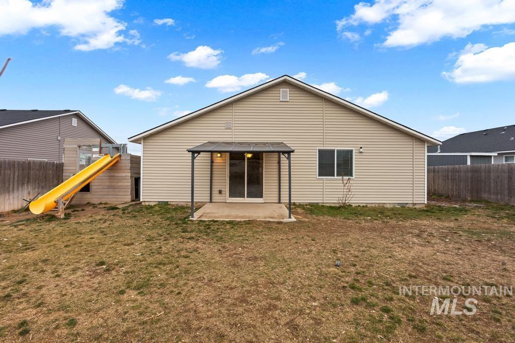 Rear view of property with a fenced backyard and a patio