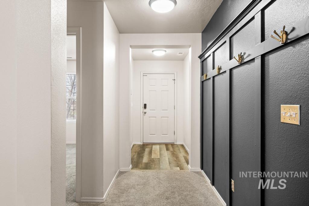 Hallway featuring a textured wall and light carpet