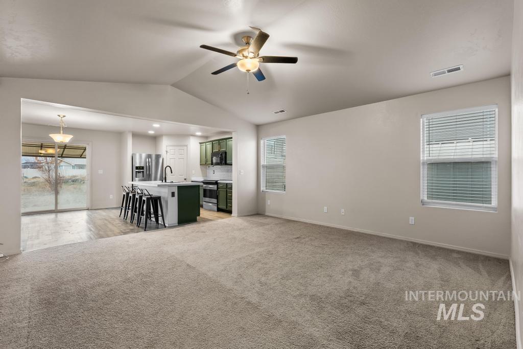 Living room with vaulted ceiling, light carpet, ceiling fan, and recessed lighting