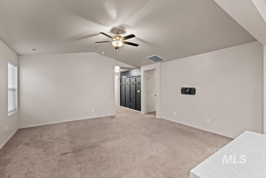 Unfurnished living room featuring light colored carpet, a ceiling fan, and lofted ceiling