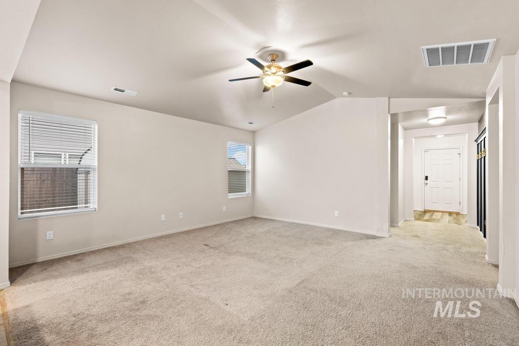 Unfurnished room with vaulted ceiling, light carpet, and a ceiling fan