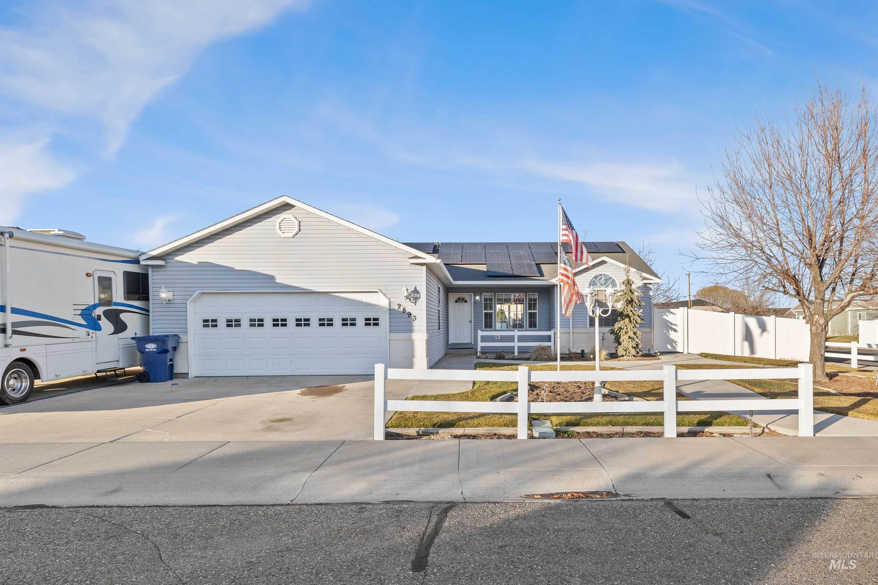 Ranch-style house featuring concrete driveway, roof mounted solar panels, an attached garage, and a porch