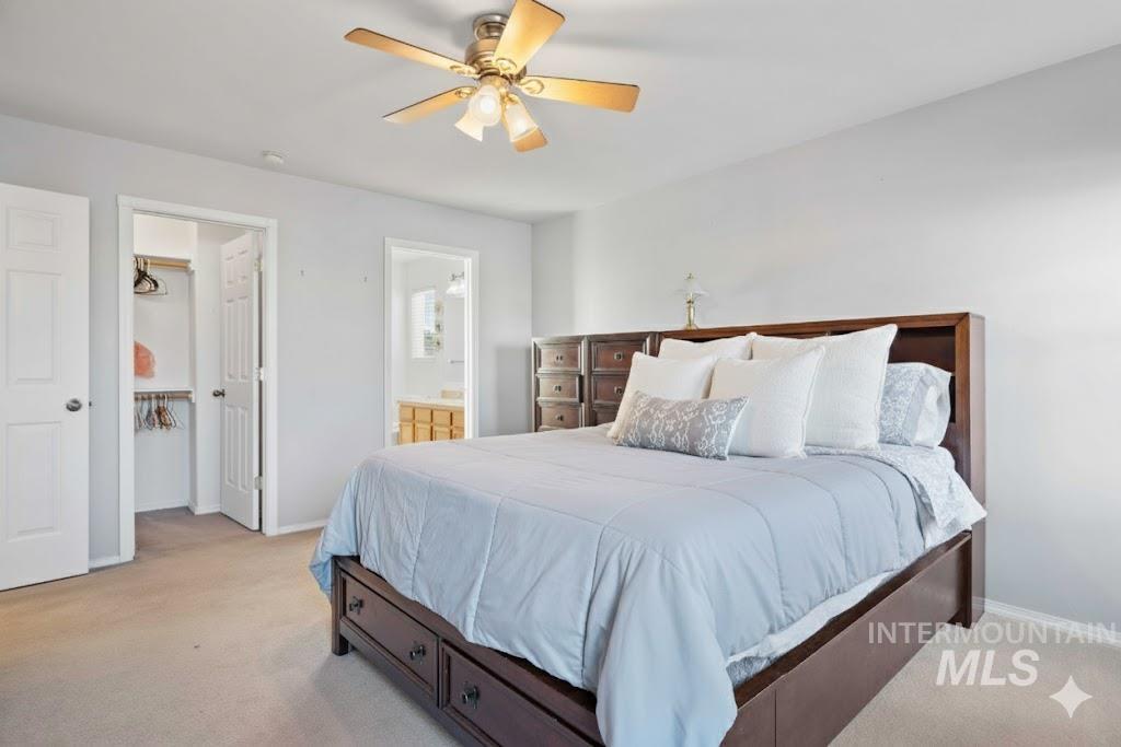 Bedroom featuring light carpet, ceiling fan, and ensuite bathroom