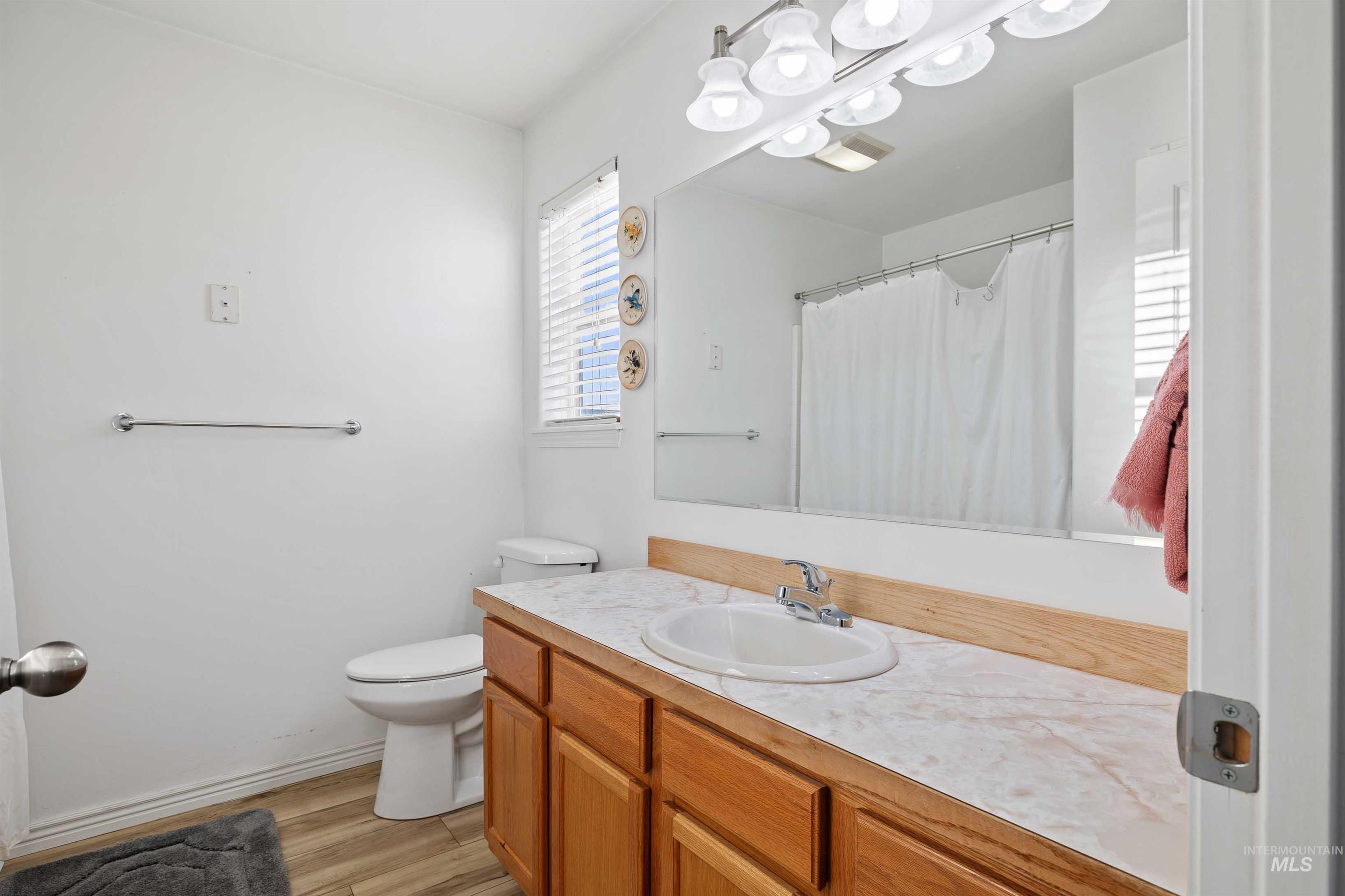 Full bathroom featuring vanity, light wood-style floors, curtained shower, and a chandelier