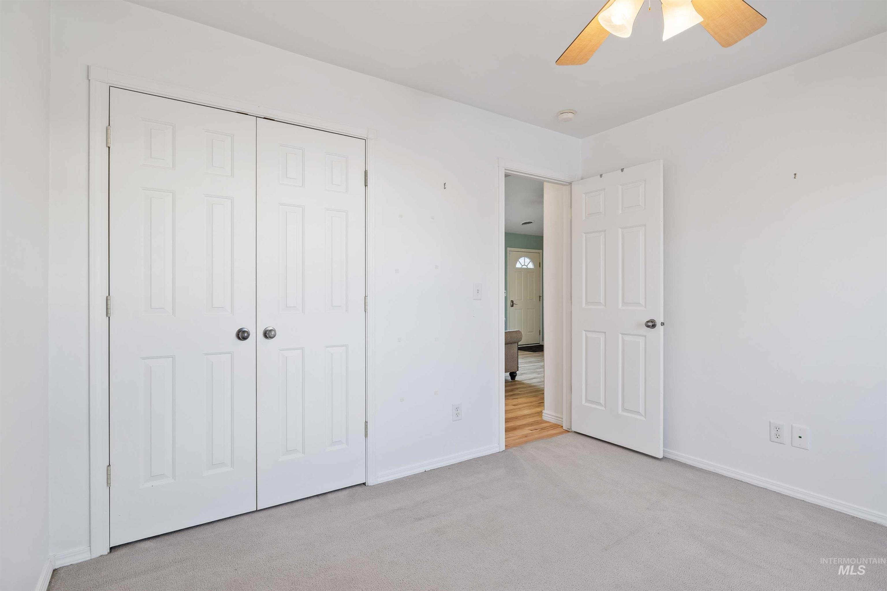 Unfurnished bedroom with light colored carpet, ceiling fan, and a closet