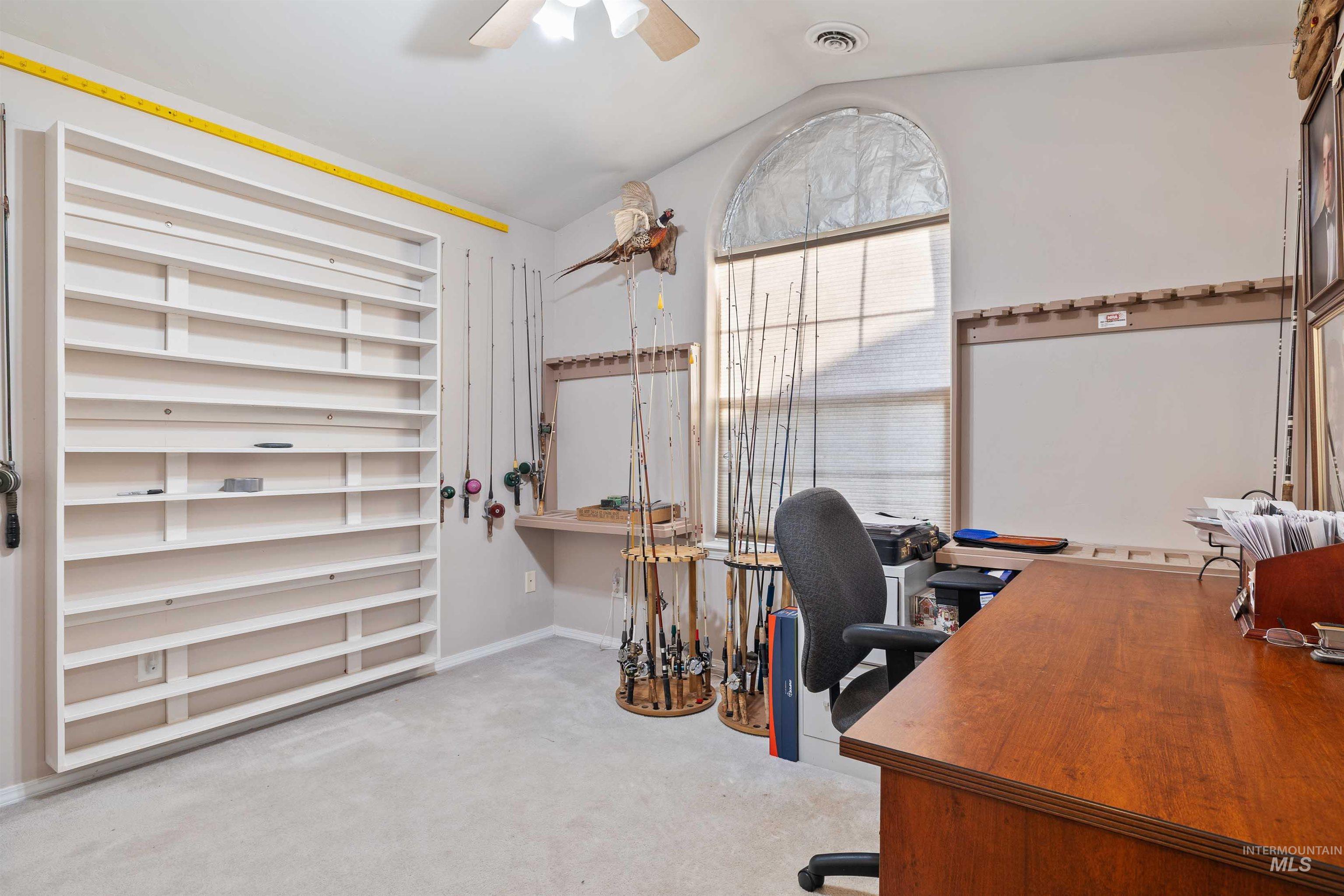 Home office featuring lofted ceiling, light carpet, and ceiling fan