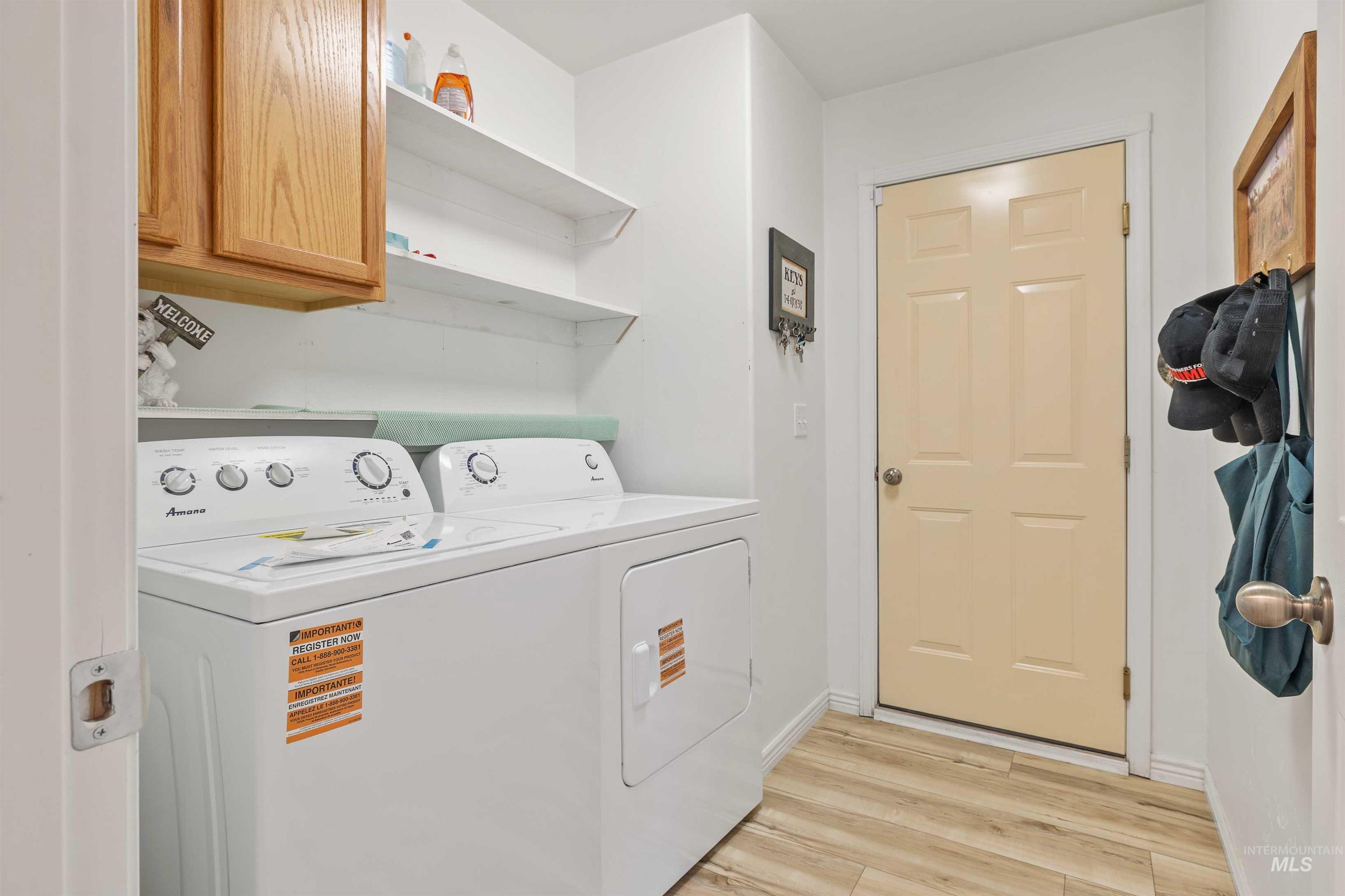 Laundry room with cabinet space, light wood-style flooring, and separate washer and dryer