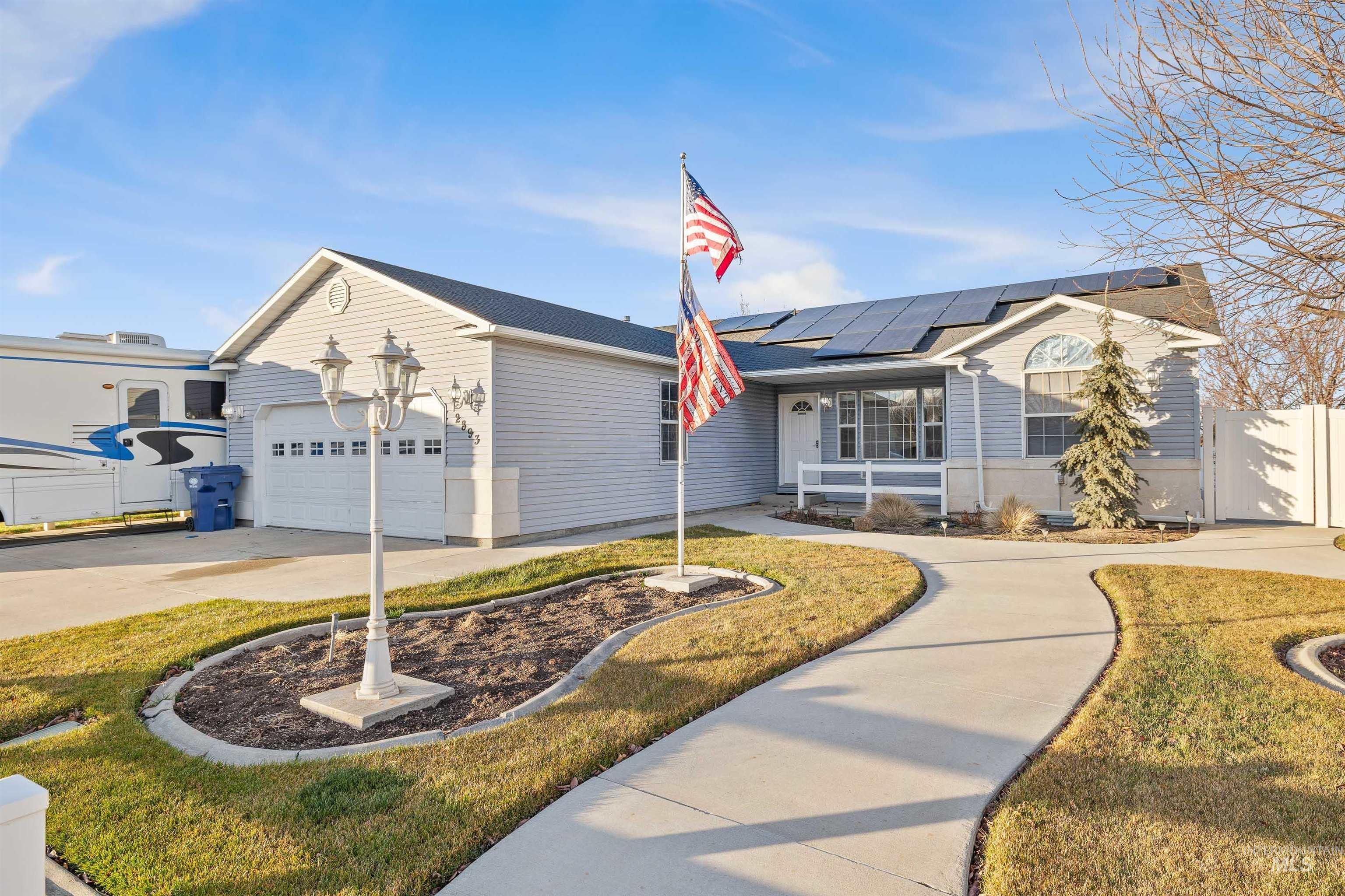 Ranch-style home featuring driveway and roof mounted solar panels