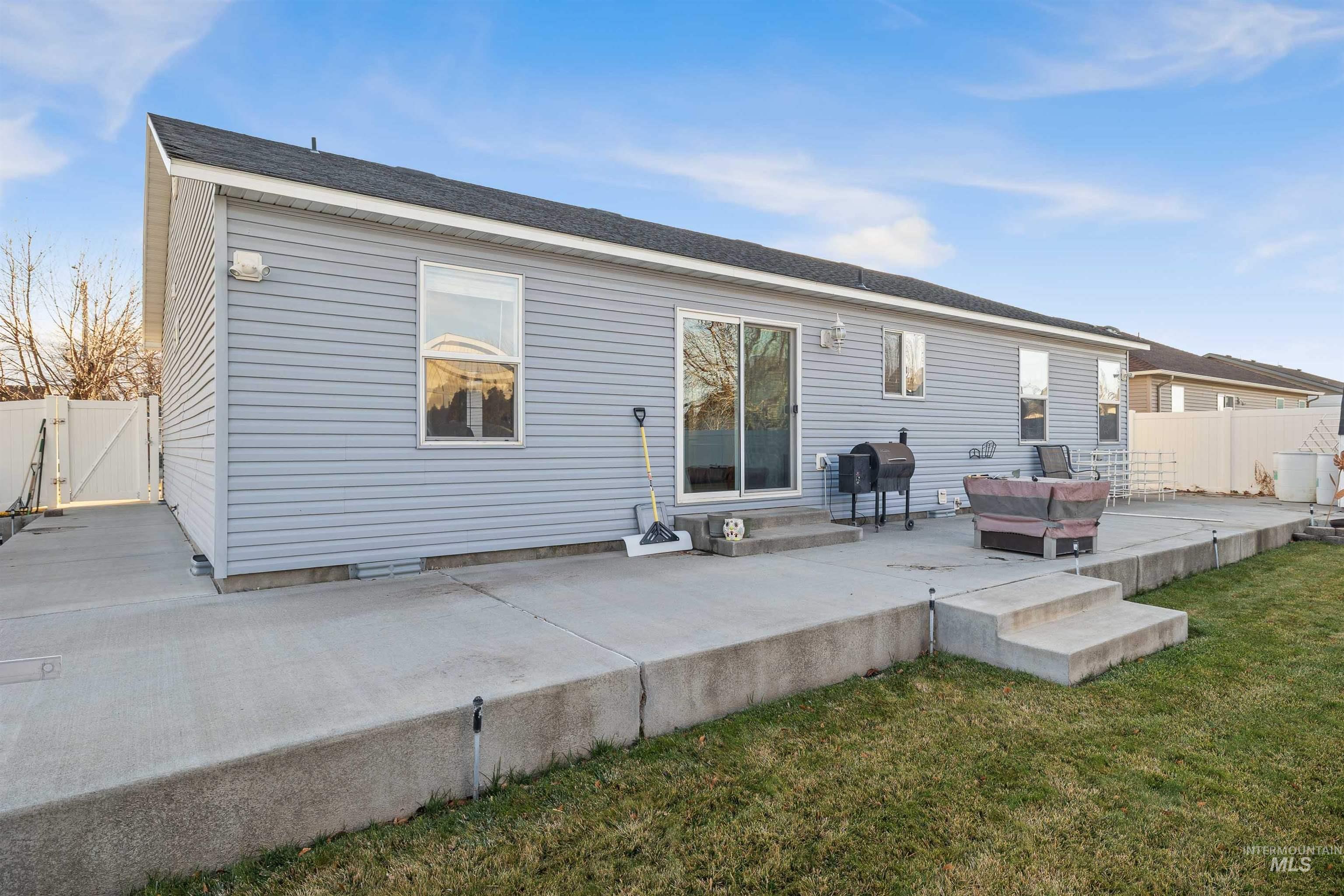 Rear view of house featuring a patio area, a gate, and roof with shingles