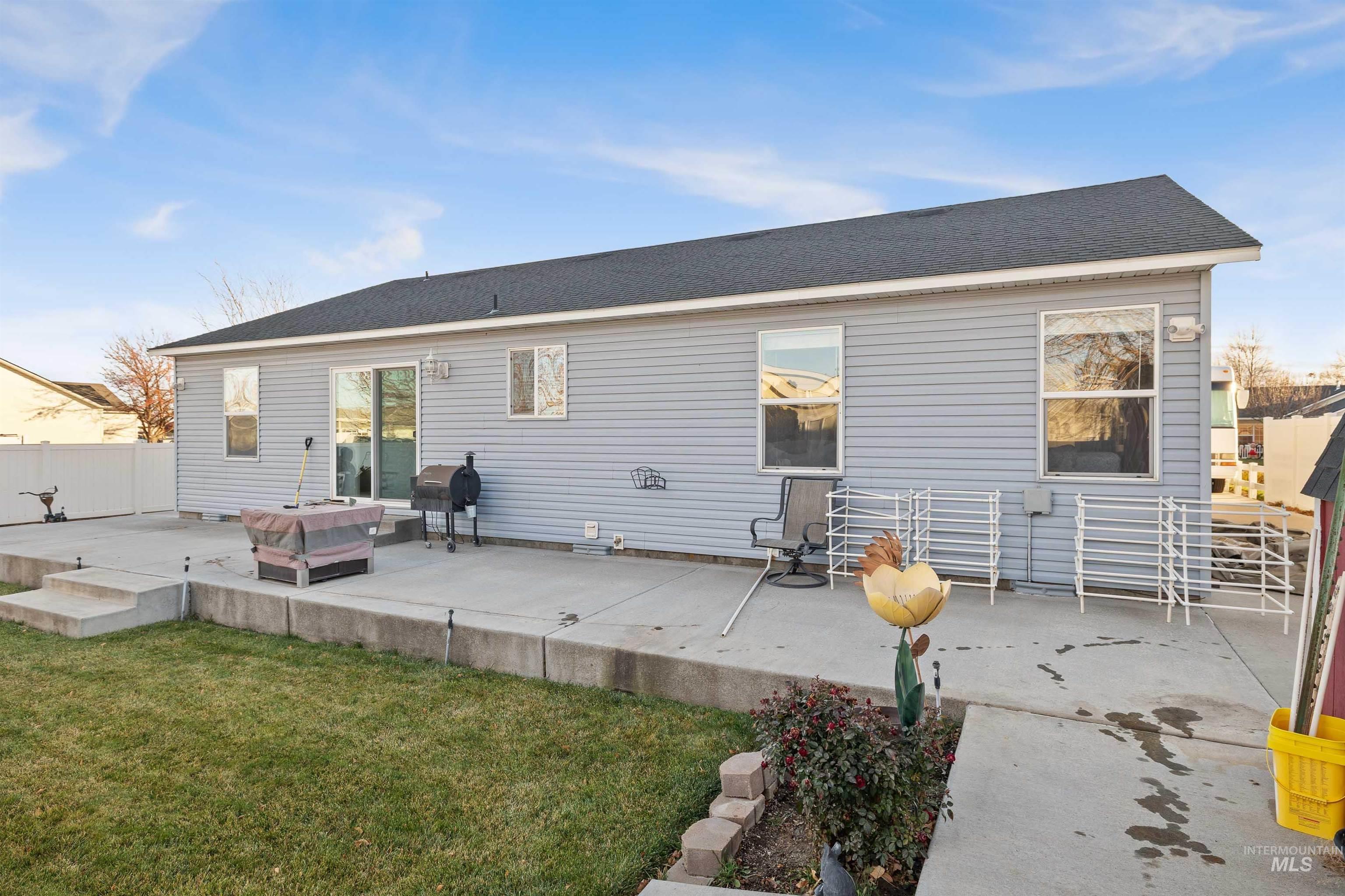 Back of house featuring a patio area and roof with shingles