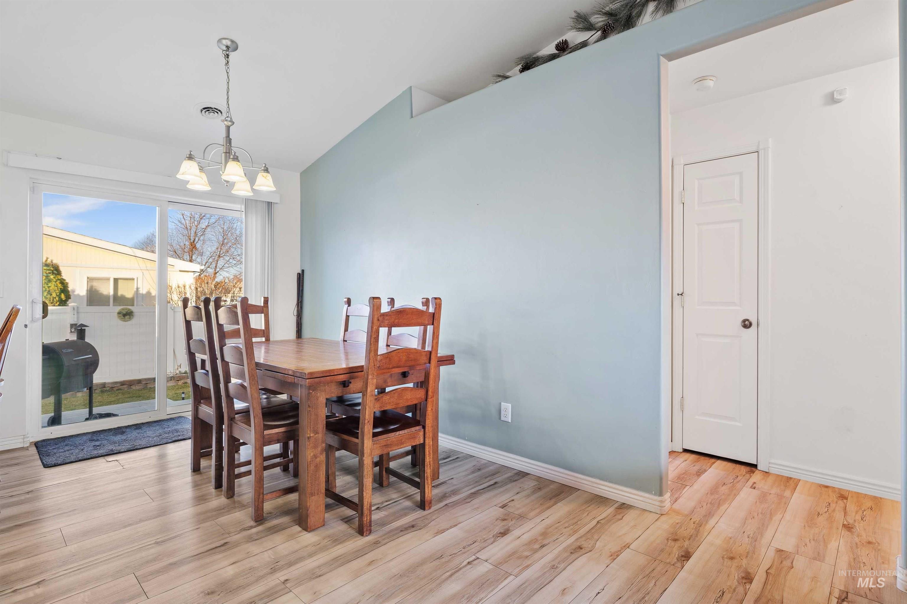 Dining room with light wood-style flooring, a chandelier, and lofted ceiling