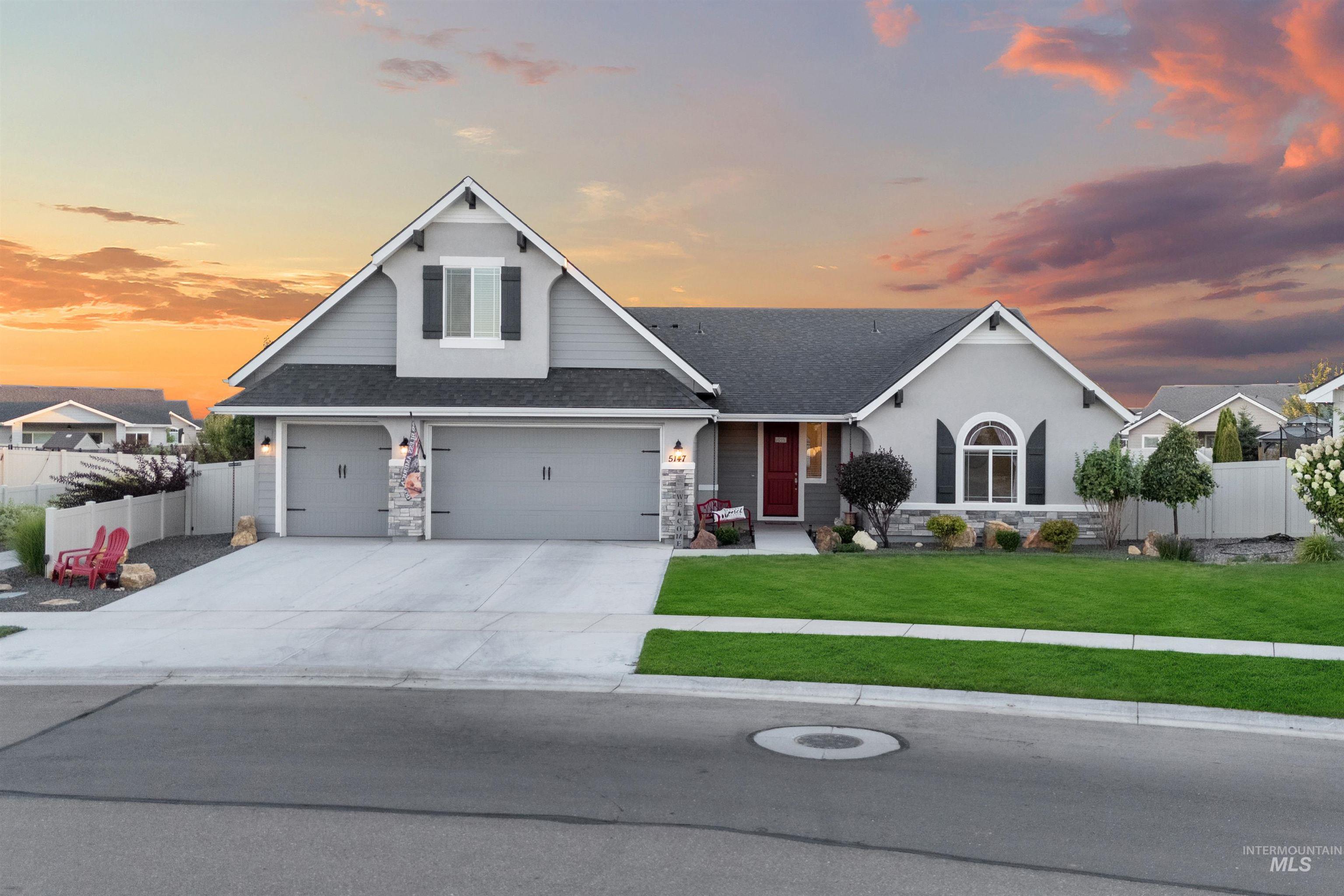 Traditional home featuring stone siding, a shingled roof, driveway, stucco siding, and a garage