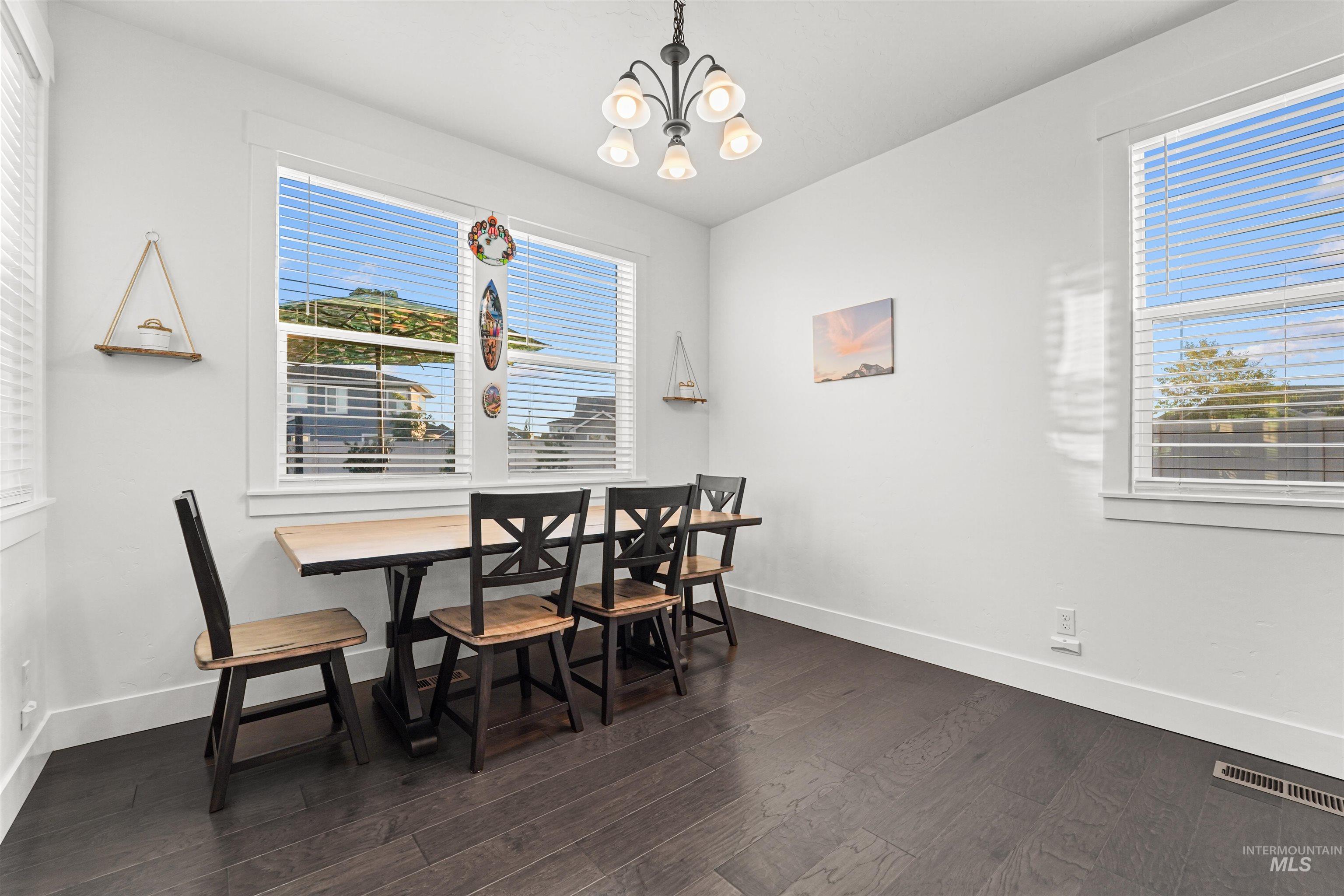 Dining space featuring healthy amount of natural light, dark wood-type flooring, and a chandelier