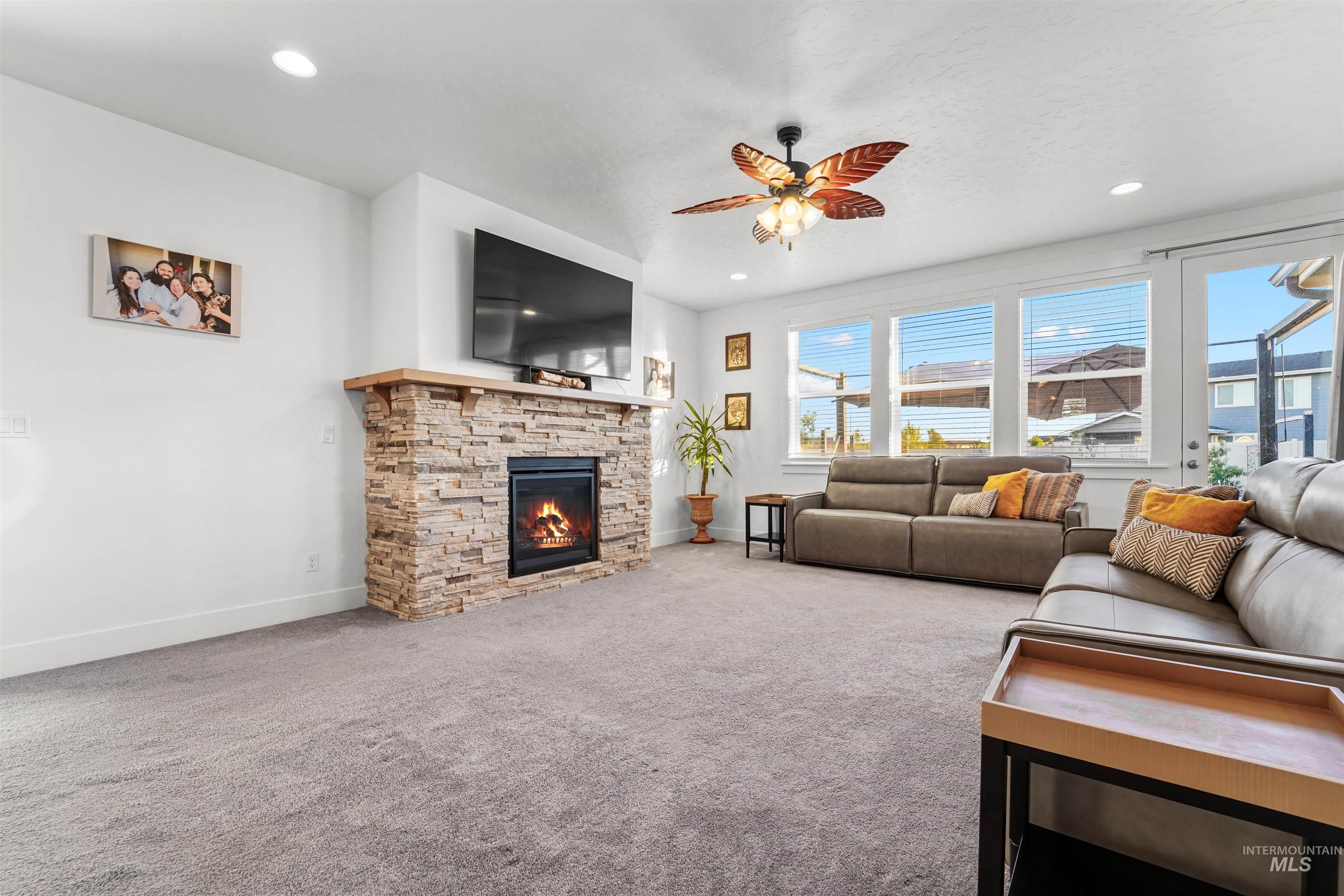 Living room with light colored carpet, a fireplace, ceiling fan, and recessed lighting