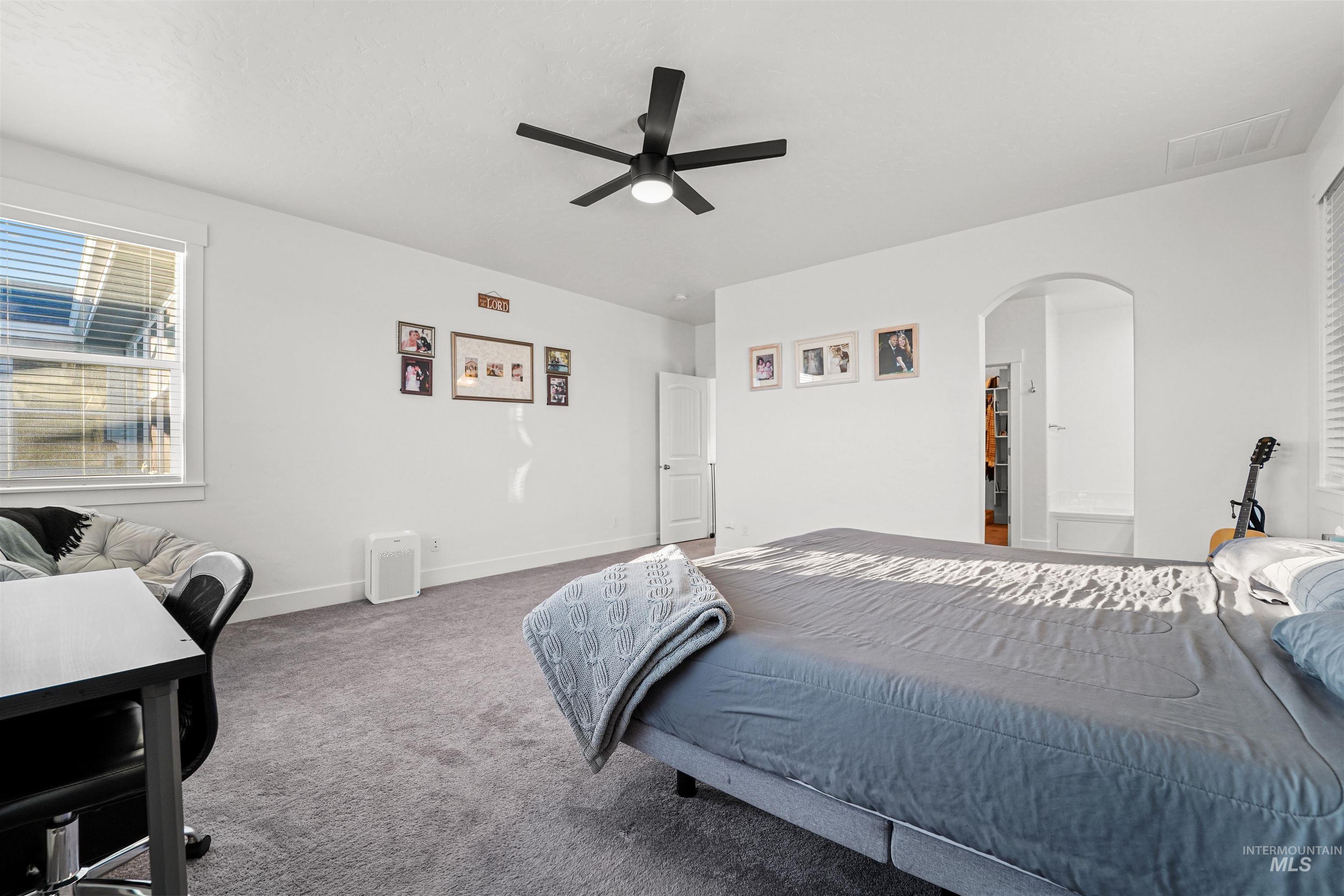 Bedroom featuring carpet flooring, arched walkways, and a ceiling fan