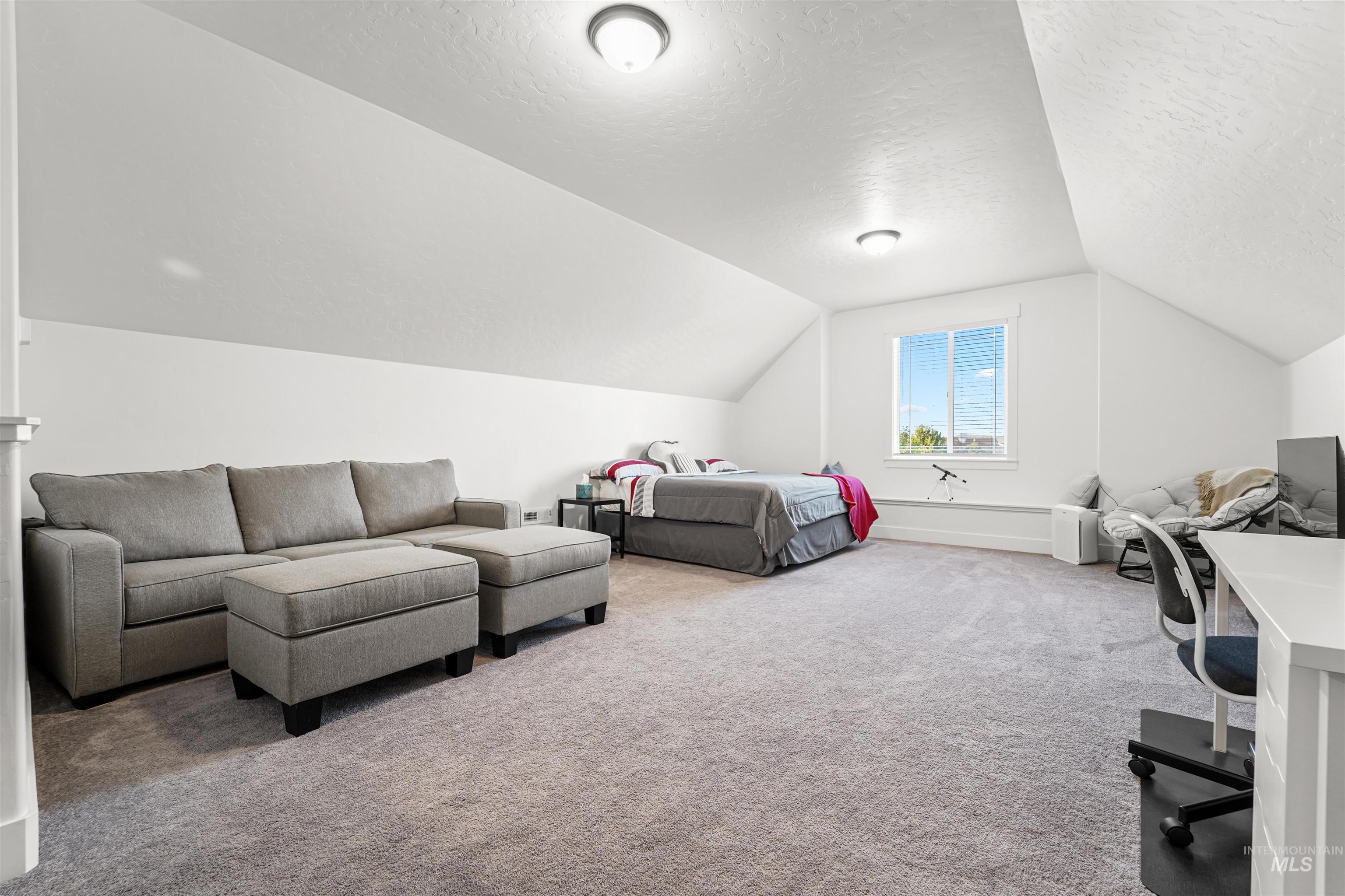 Bedroom with carpet flooring, a textured ceiling, and vaulted ceiling