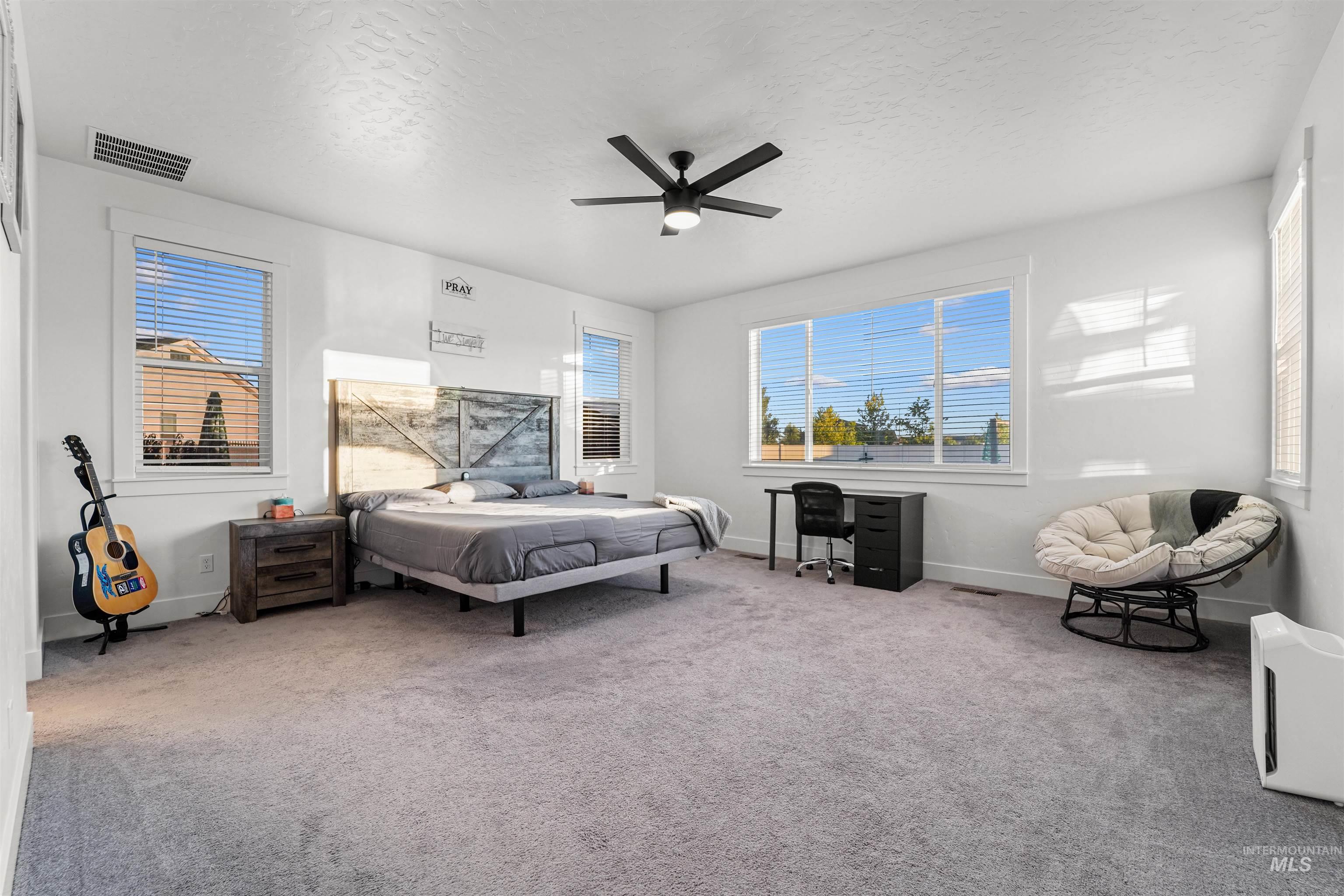 Bedroom with a textured ceiling, carpet floors, and a ceiling fan