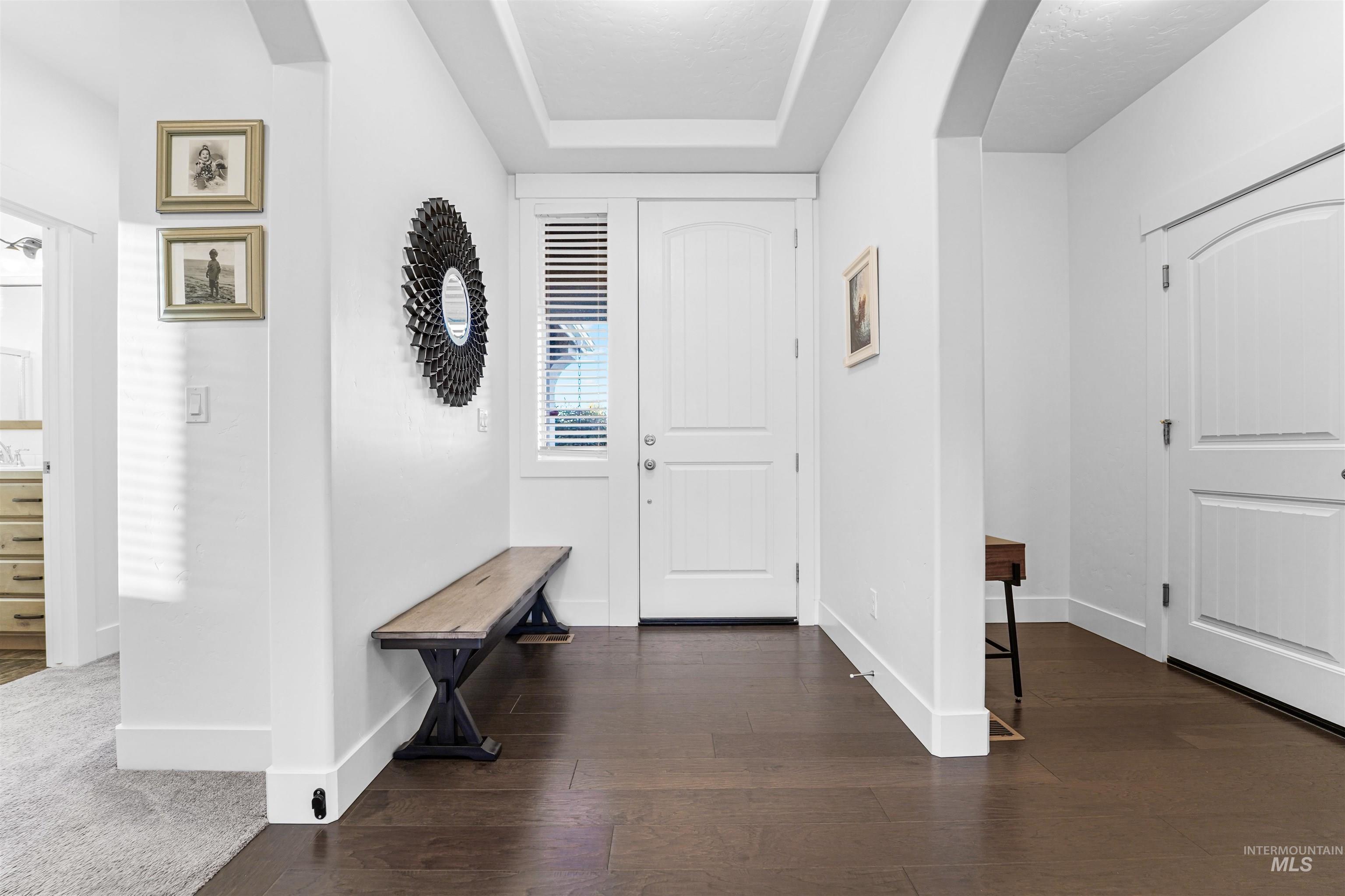 Entrance foyer featuring arched walkways, dark wood-style floors, and a tray ceiling