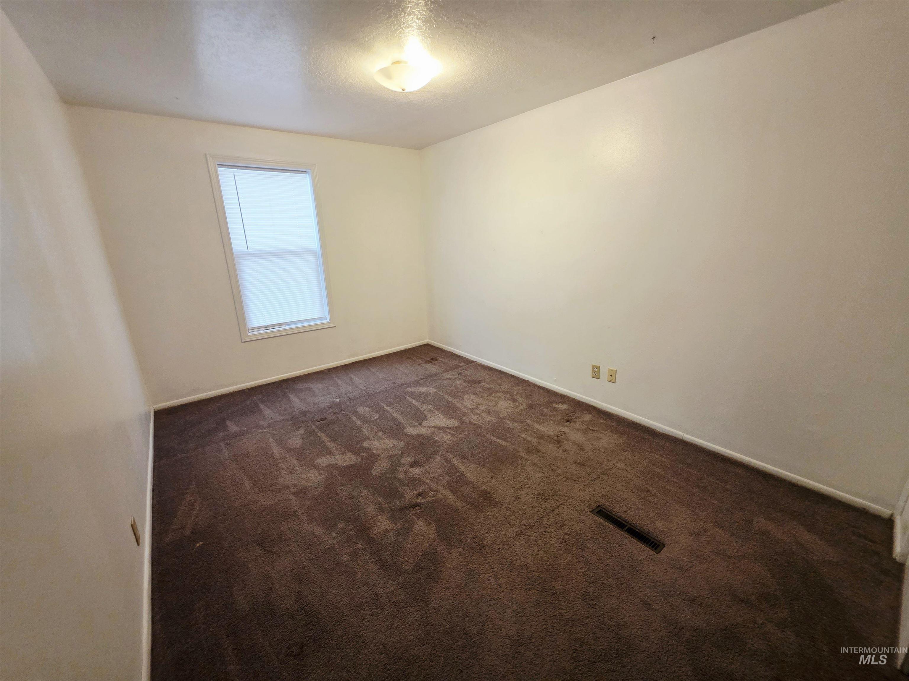 Spare room with a textured ceiling and dark carpet